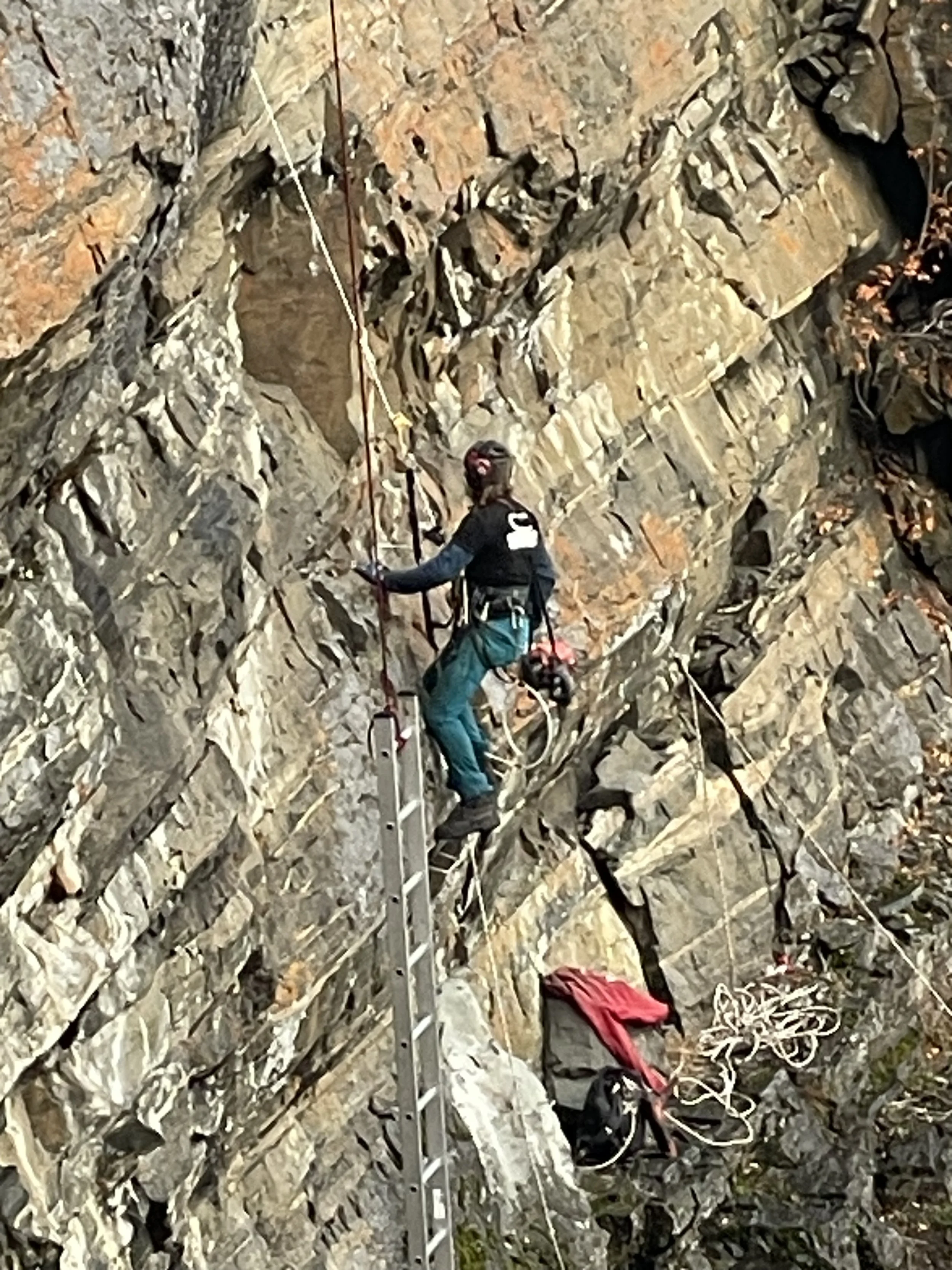 En klatre som bruker utstyr, som hjelm og tau, på en fjellvegg.
