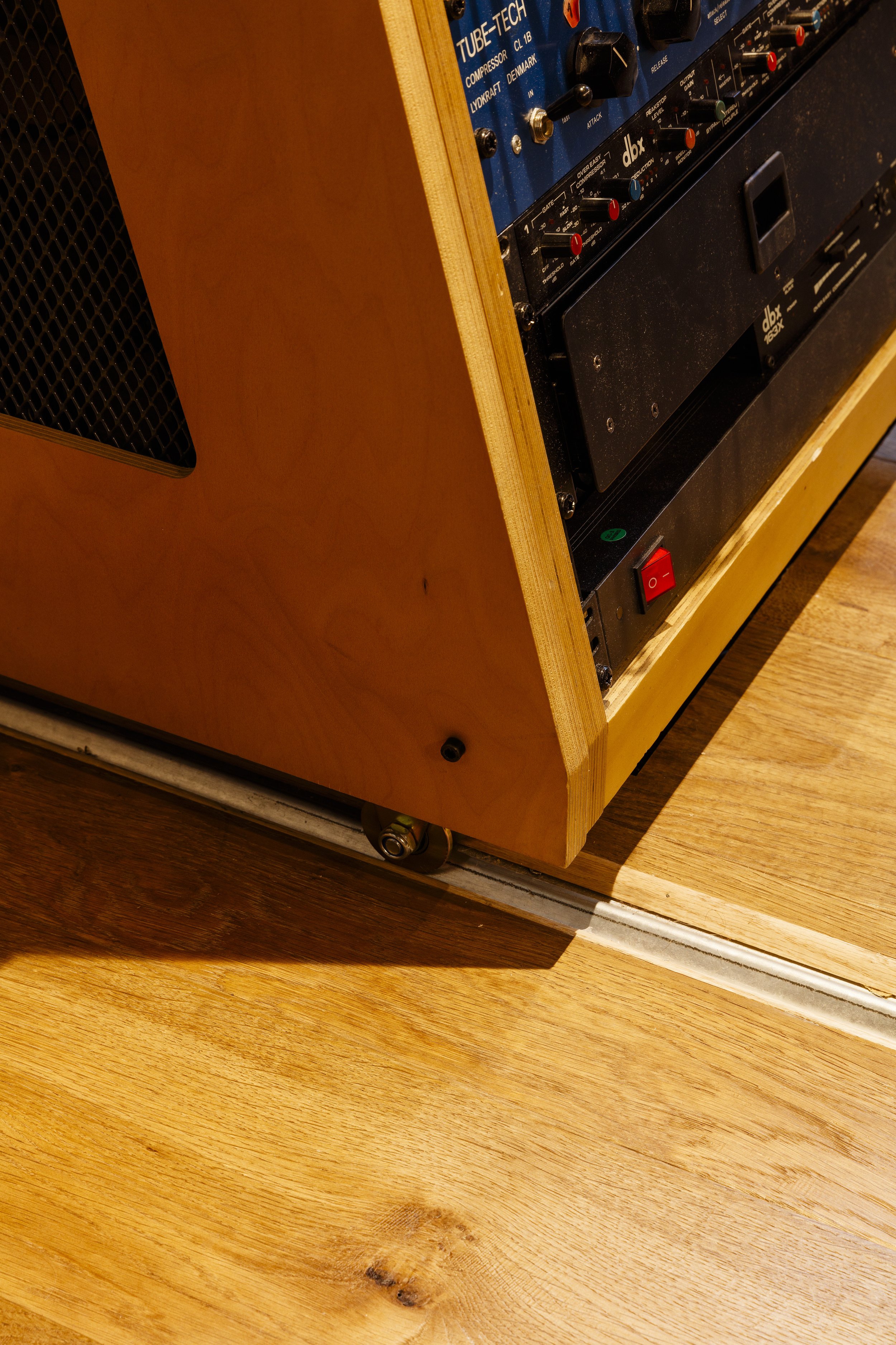 Une partie d'un amplificateur ou d'un équipement audio sur un support en bois, avec des boutons de contrôle et un interrupteur rouge visible.