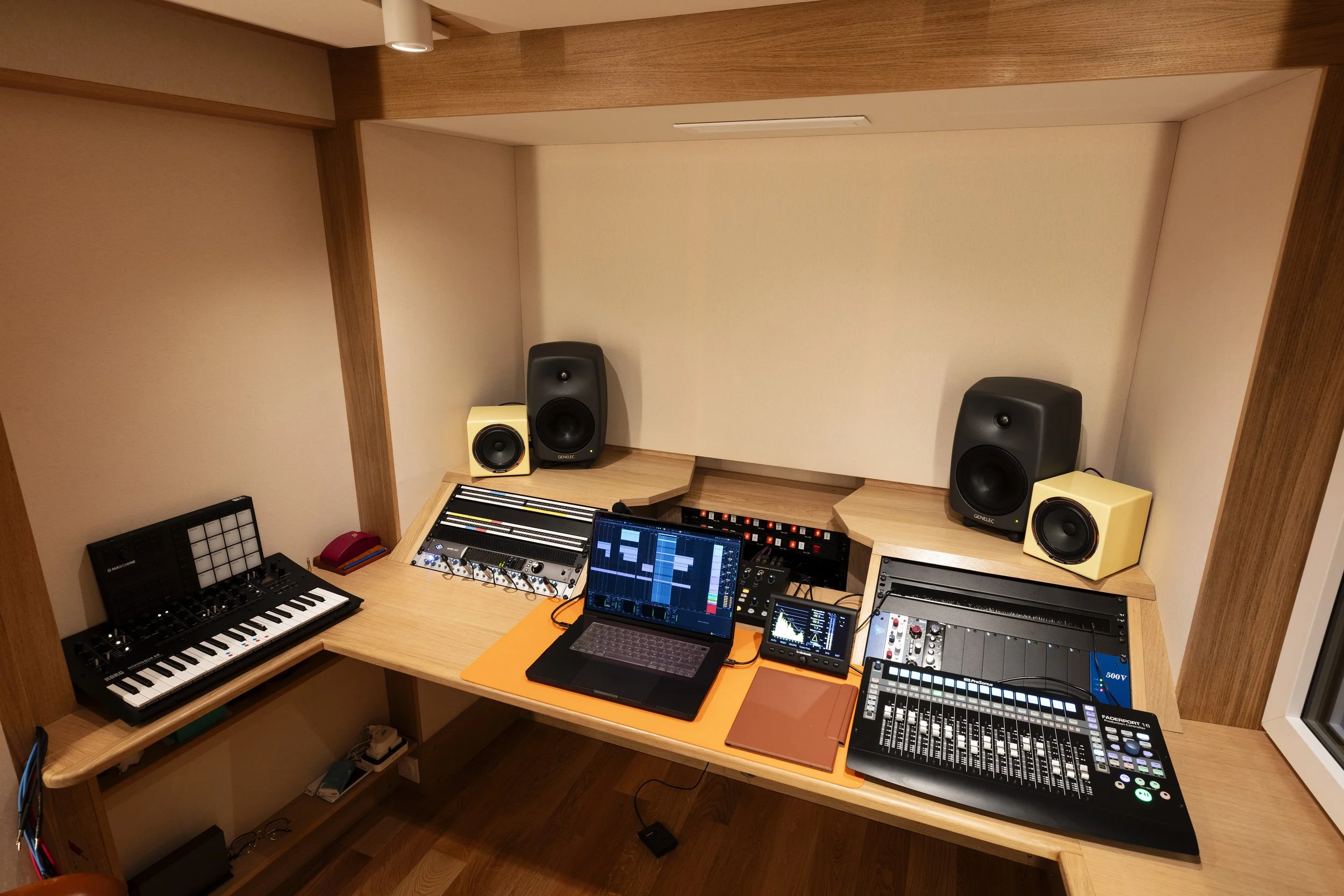 Studio d'enregistrement avec des équipements audio, une console de mixage, des haut-parleurs, un clavier MIDI, un ordinateur avec logiciel de production musicale, et divers dispositifs audio.