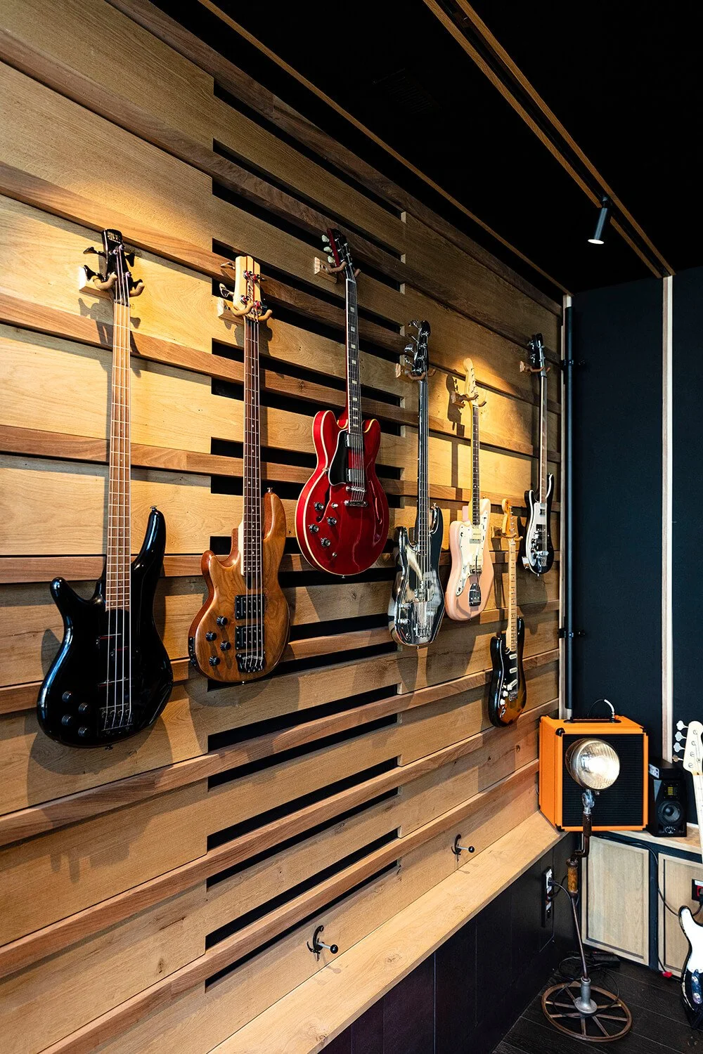 Une collection de guitares électriques accrochées à un mur en bois dans un studio de musique.