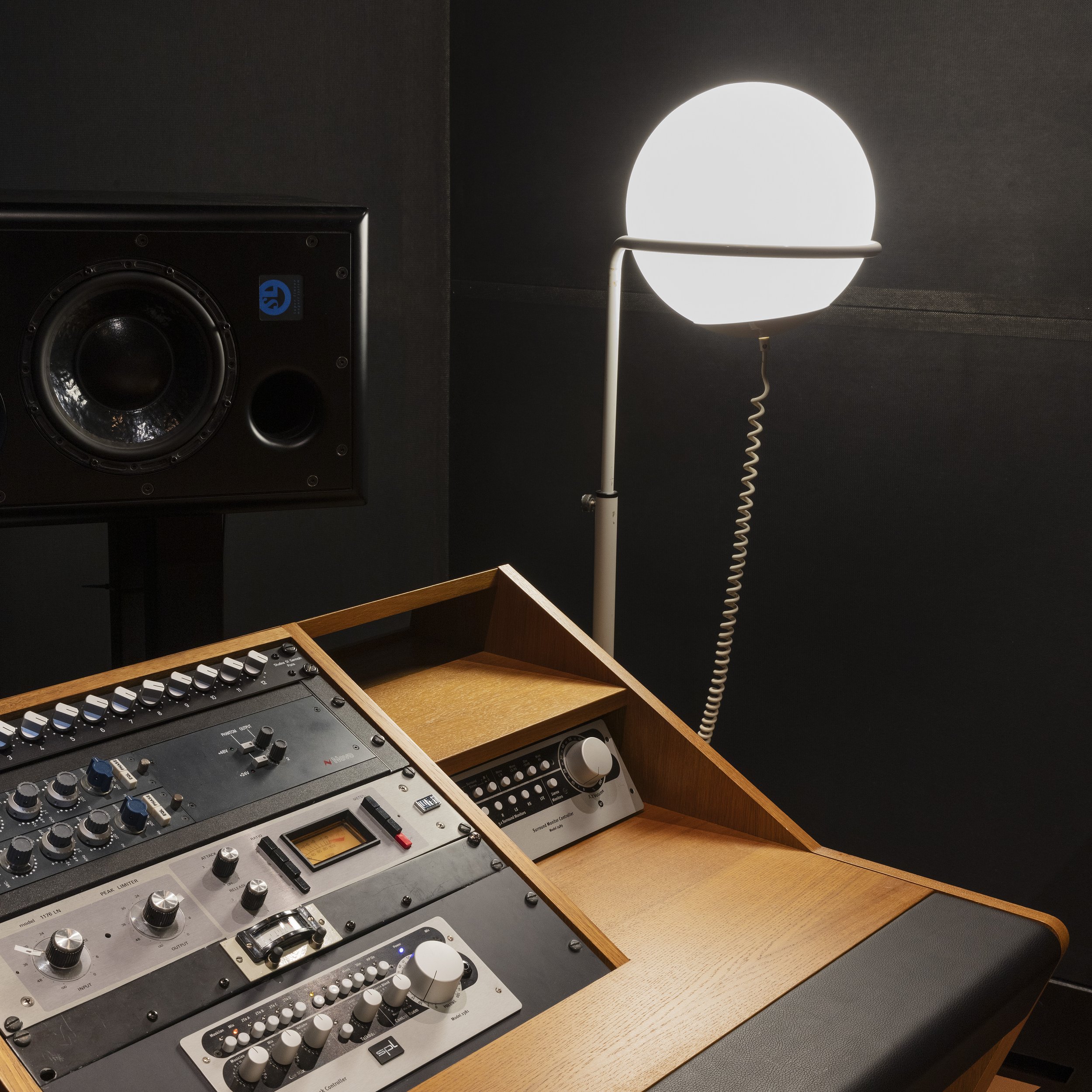 Studio d'enregistrement avec une console de mixage, un haut-parleur et une lampe sur pied.
