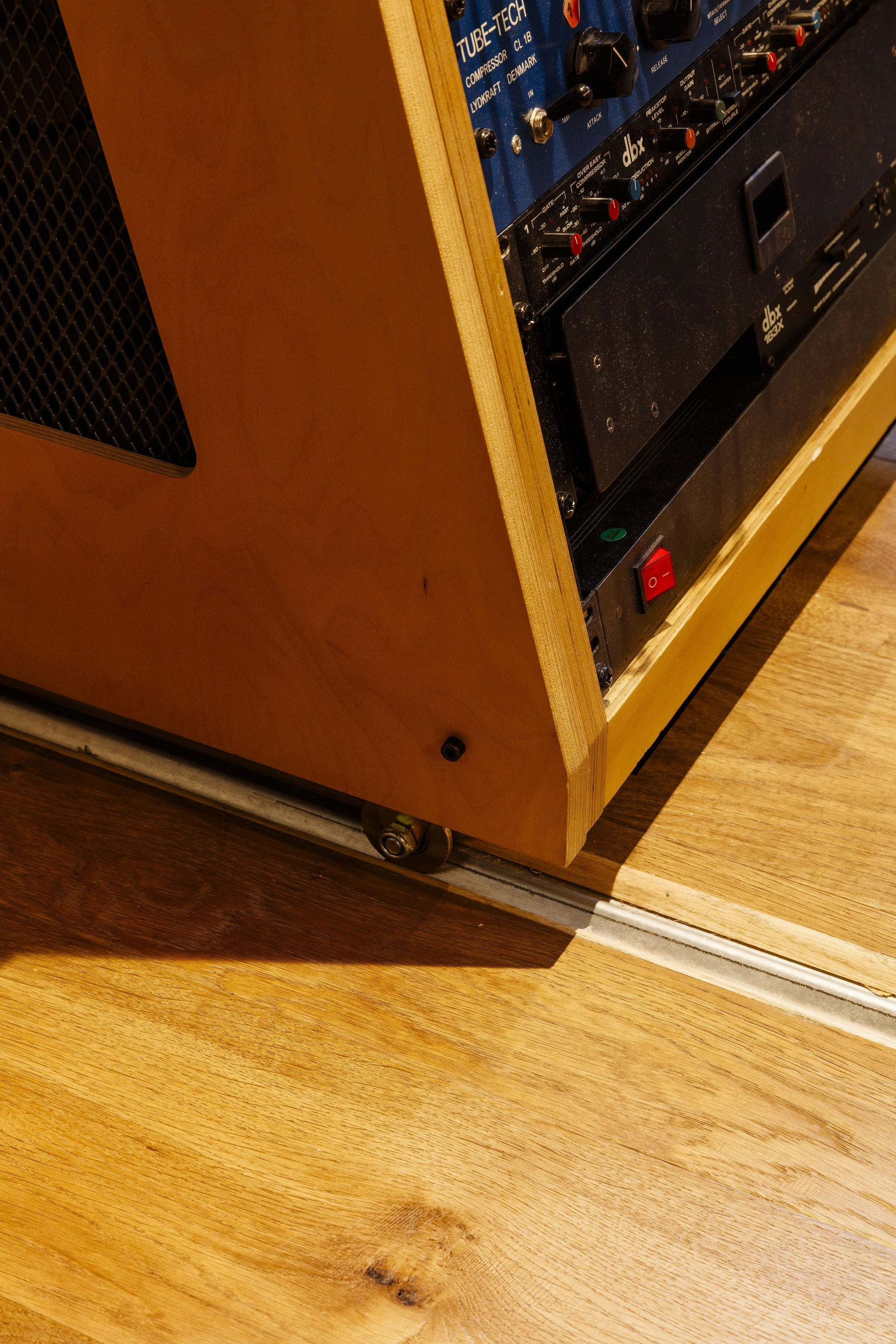 Une partie d'un amplificateur ou d'un équipement audio sur un support en bois, avec des boutons de contrôle et un interrupteur rouge visible.