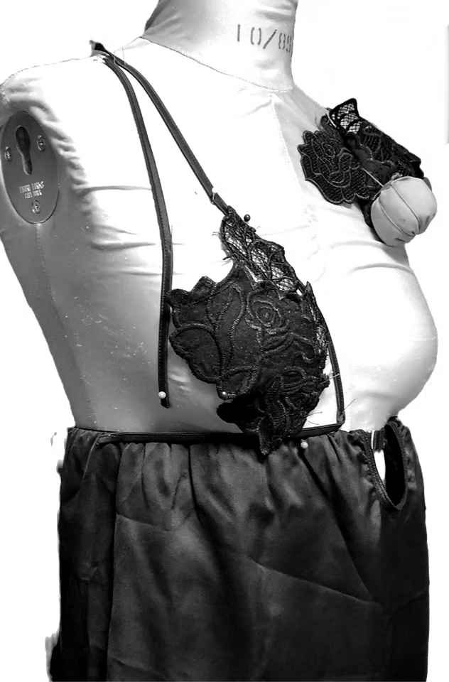 Black lace bra with floral embroidery displayed on a mannequin with a gray satin skirt.