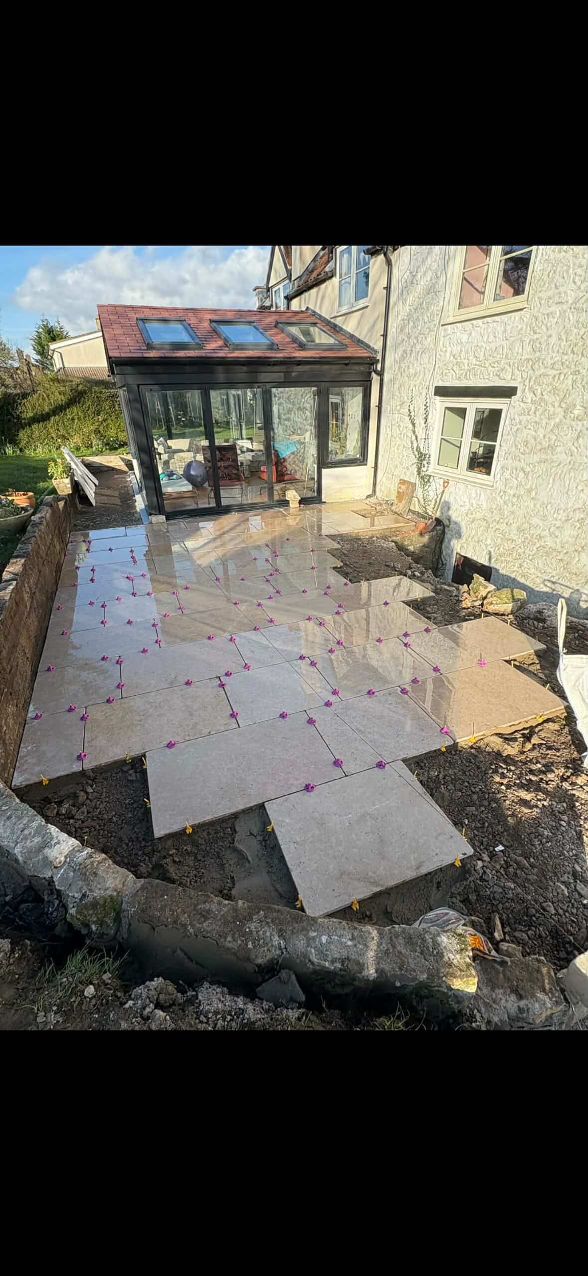 Newly laid stone patio with pink and yellow flower decorations outside a house.