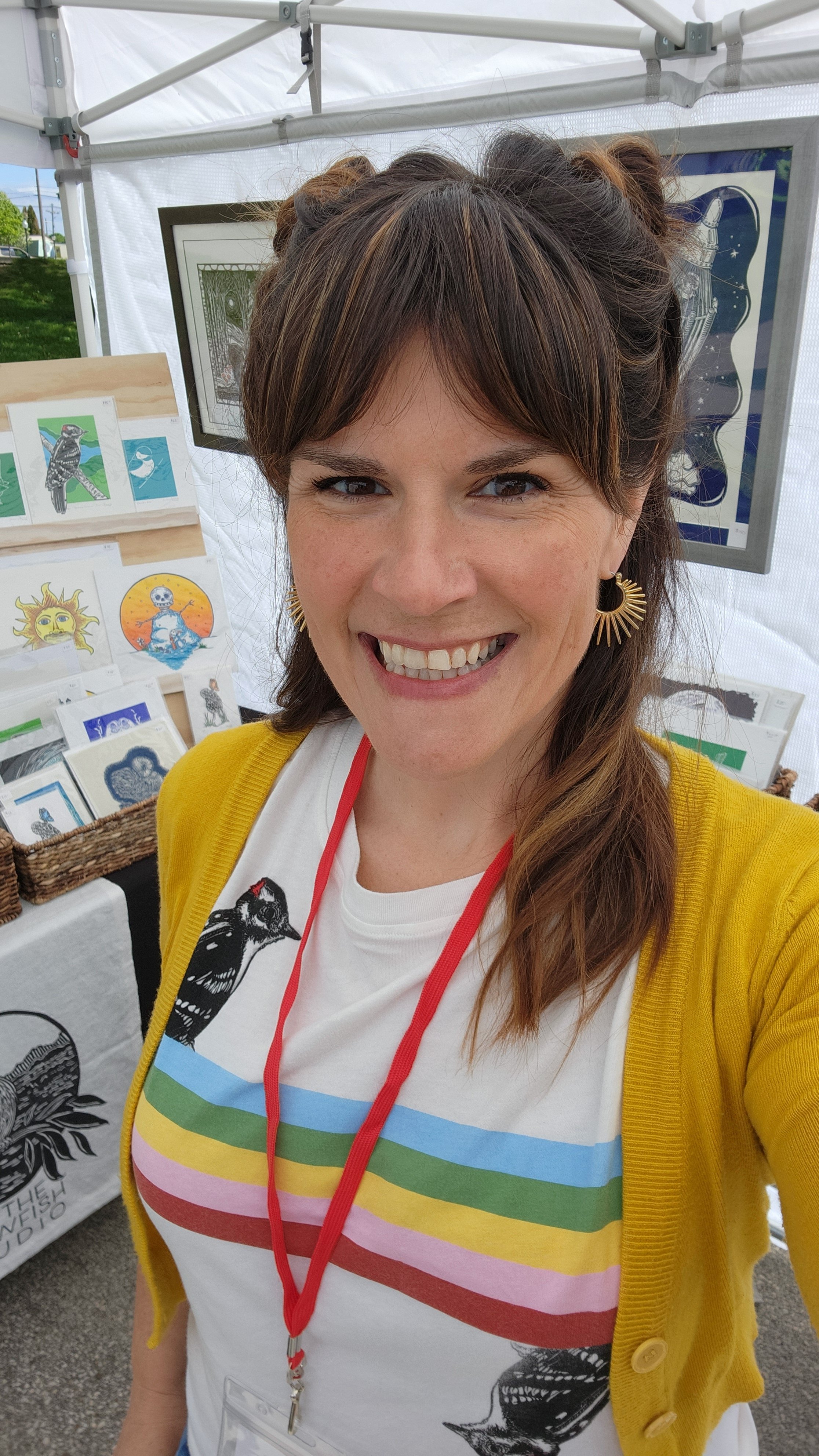 Erin Lueck smiling standing in her booth at an art fair