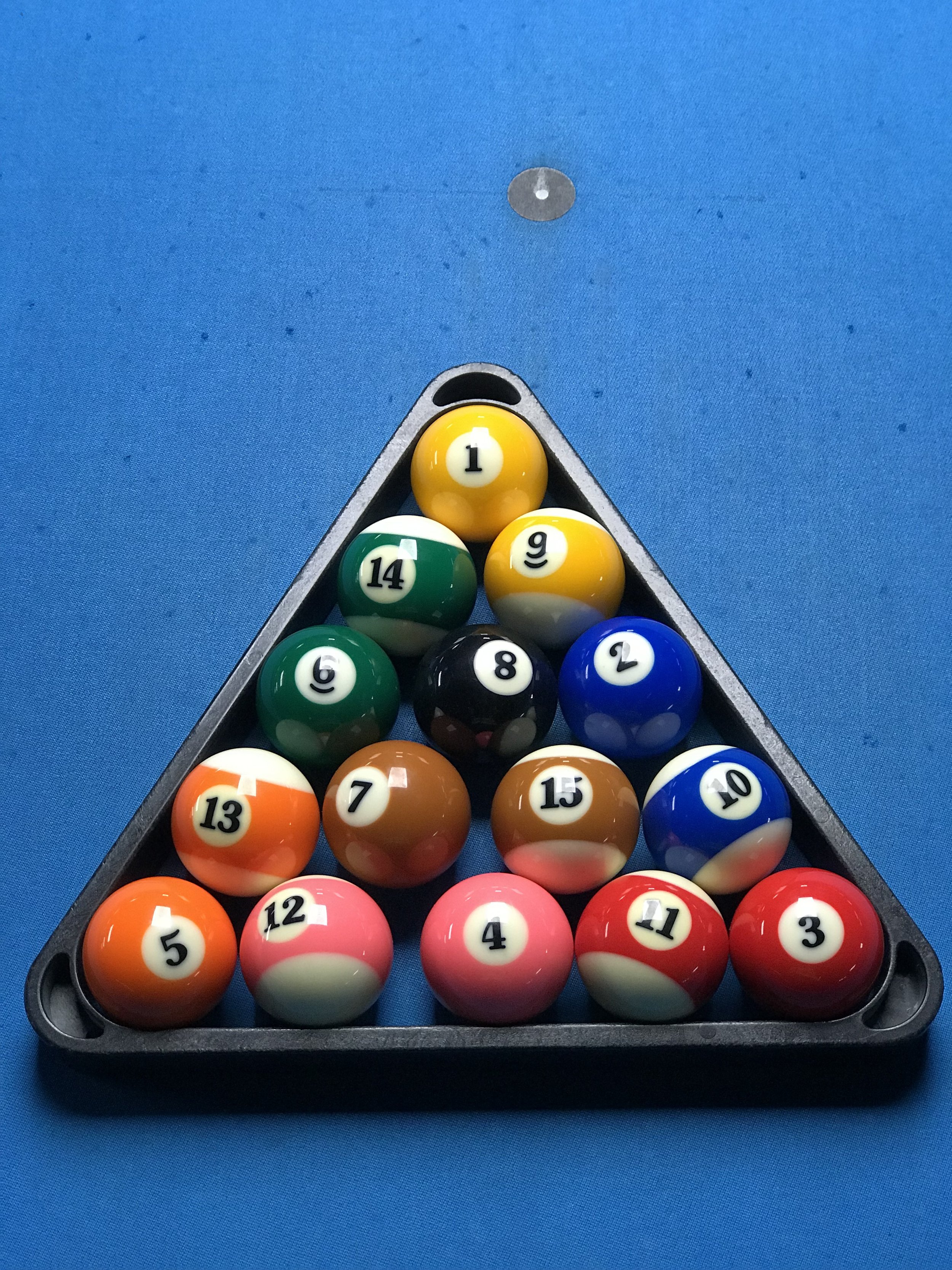 Set of fifteen billiard balls arranged in a triangle formation on a blue pool table.