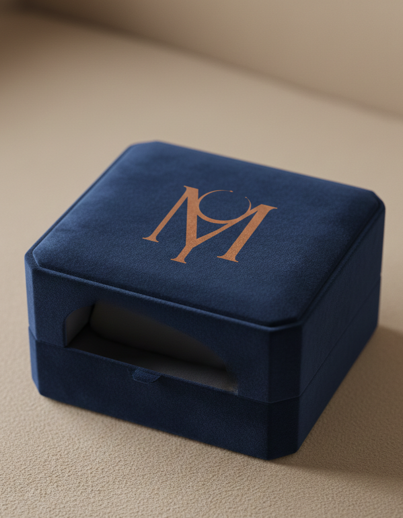 Boîte bleue en velours avec un logo doré portant l'inscription 'MAY'.