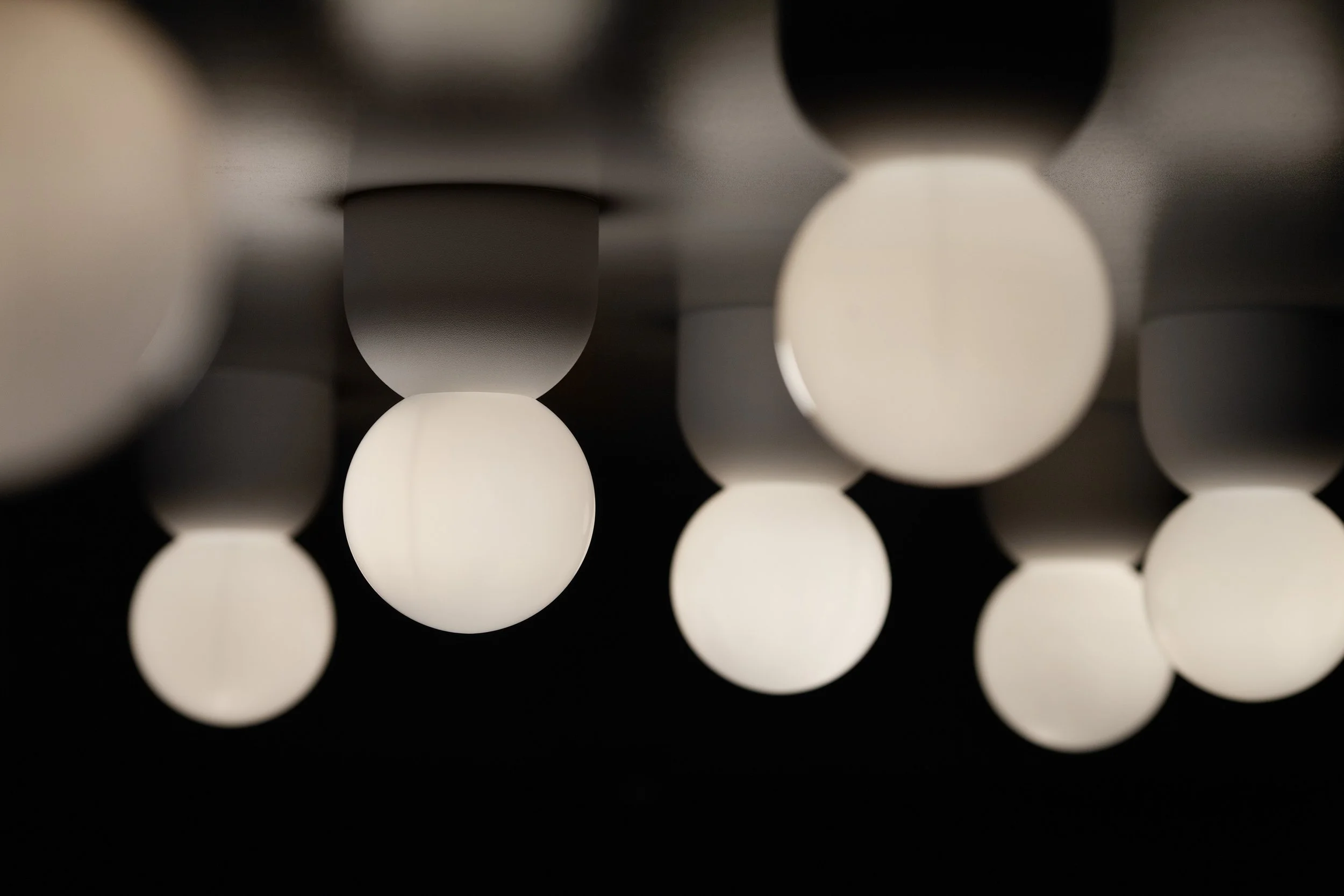 Close-up of multiple hanging spherical white and black pendant lights against a dark background.