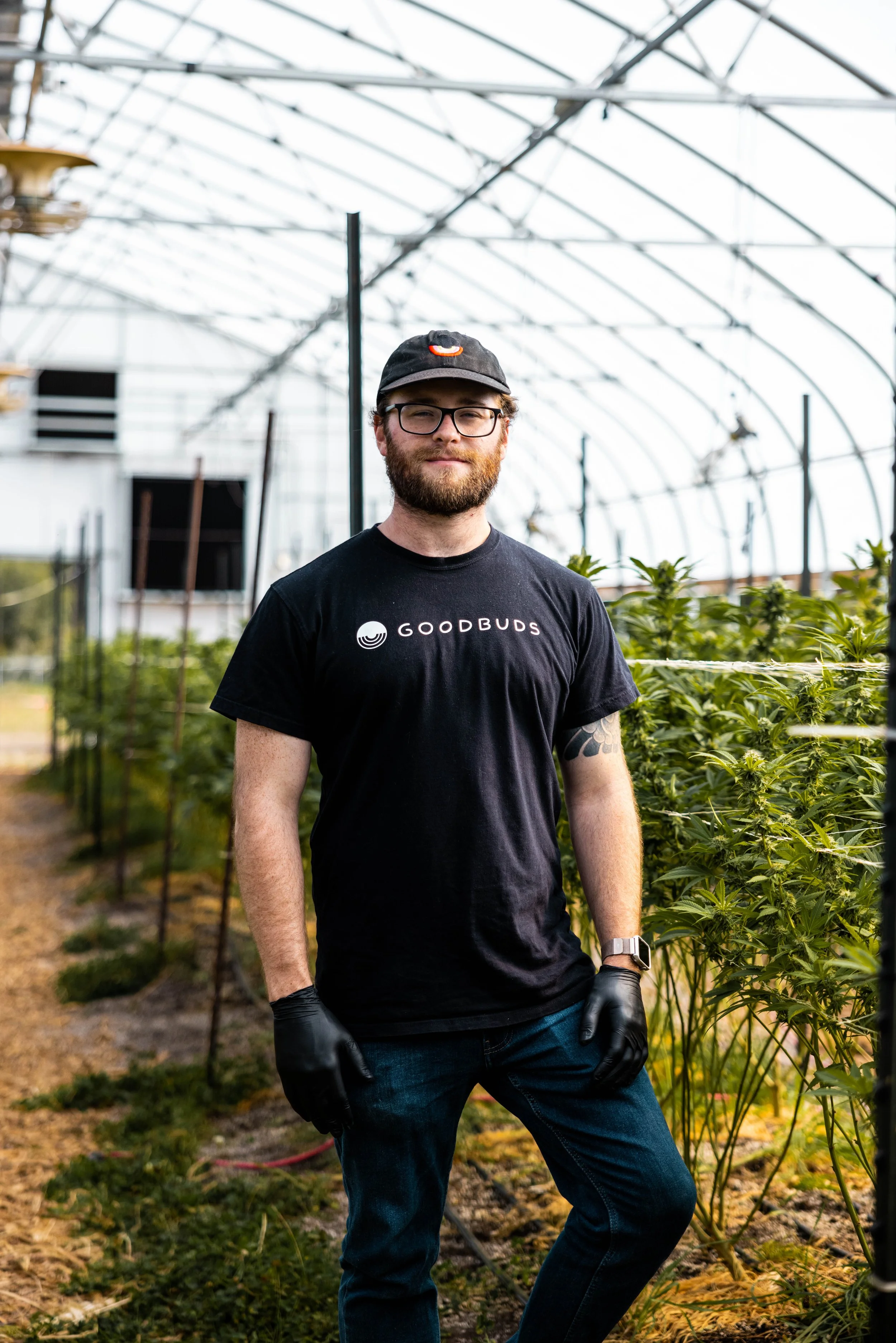 GOOD BUDS employee standing in our greenhouse with Living Soil Organic plants growing in the background