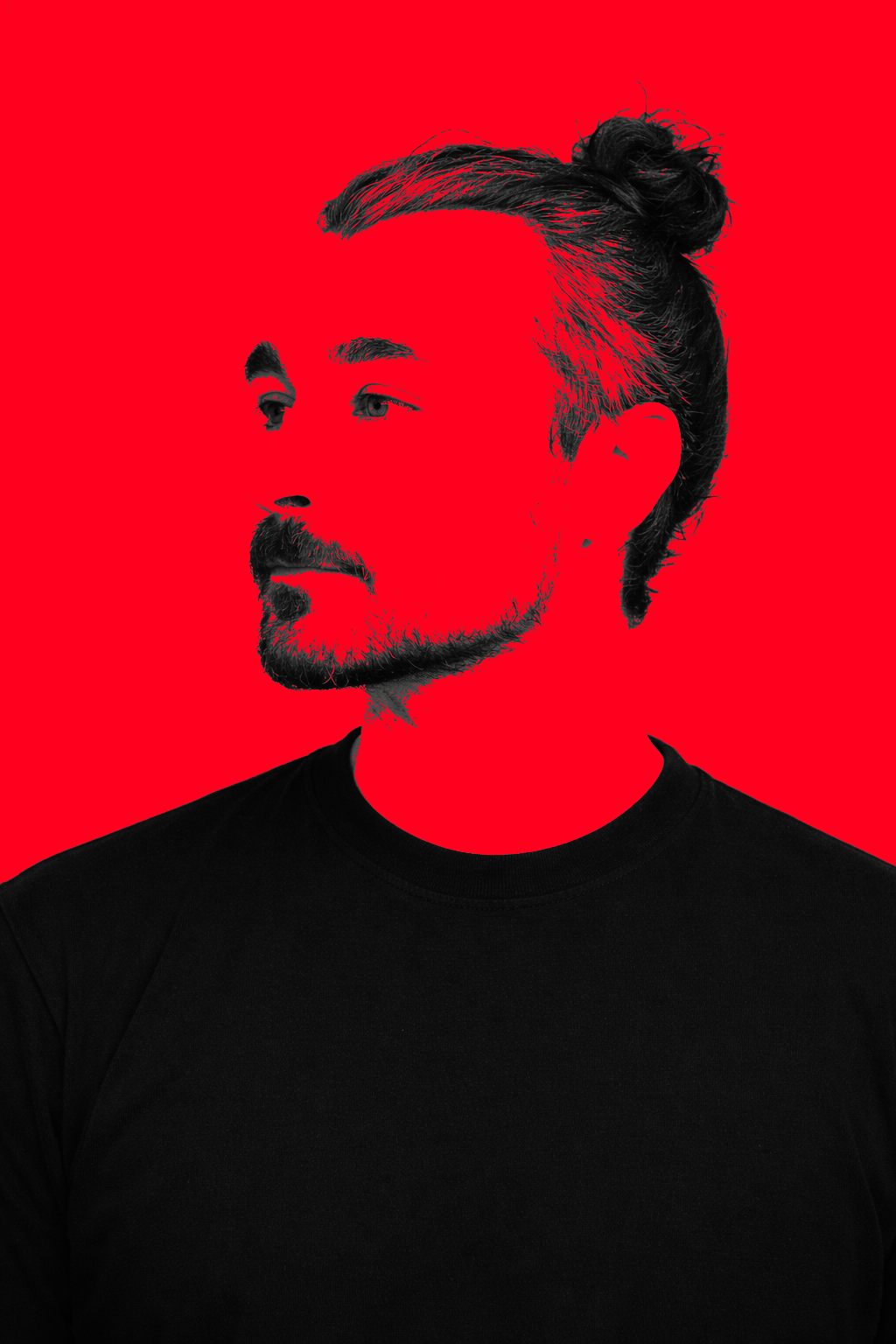 Ritratto di un uomo con barba e capelli raccolti in uno chignon, sfondo rosso, vestito nero.