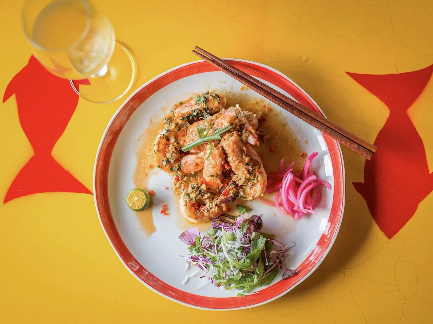 Garlic butter shrimp plated at Mango Rooms, Hoi An, served with a glass of white wine.