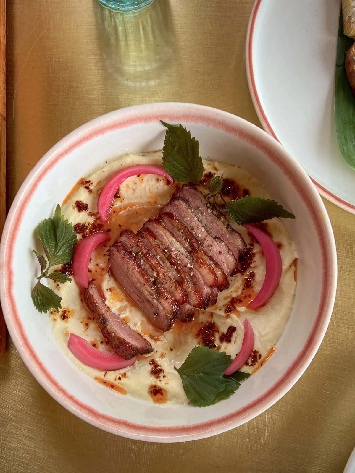 Sliced duck over a savory purée with pickled onion and herbs, a standout dish at Mango Rooms
