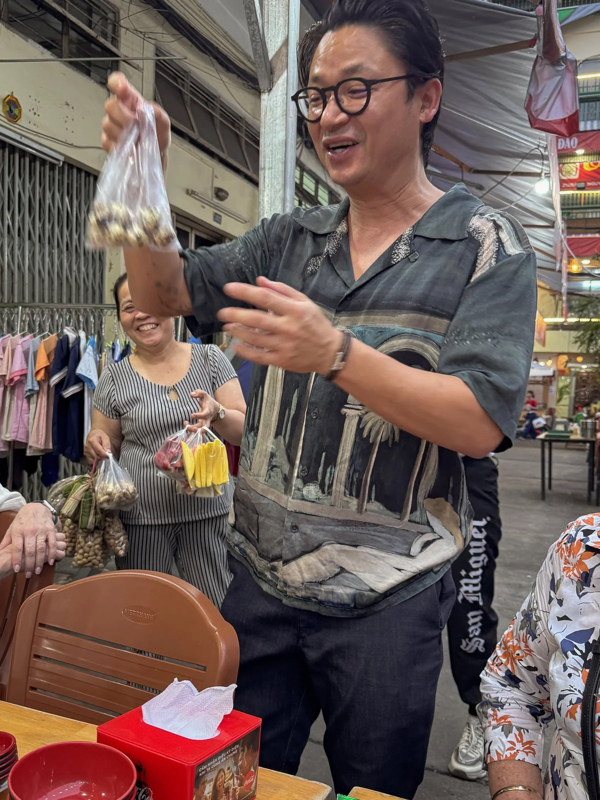 Chef Luke Nguyen holds up a bag of street snacks bought from a vendor at a Ho Chi Minh City market stall.