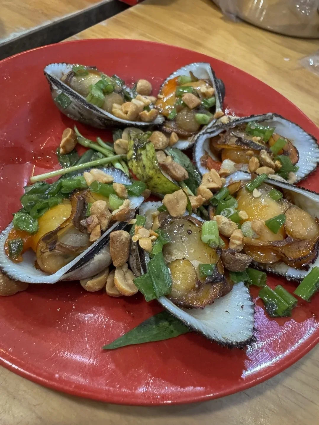 Grilled clams topped with crushed peanuts and scallions, a popular HCMC street food stop on the Vespa food tour.