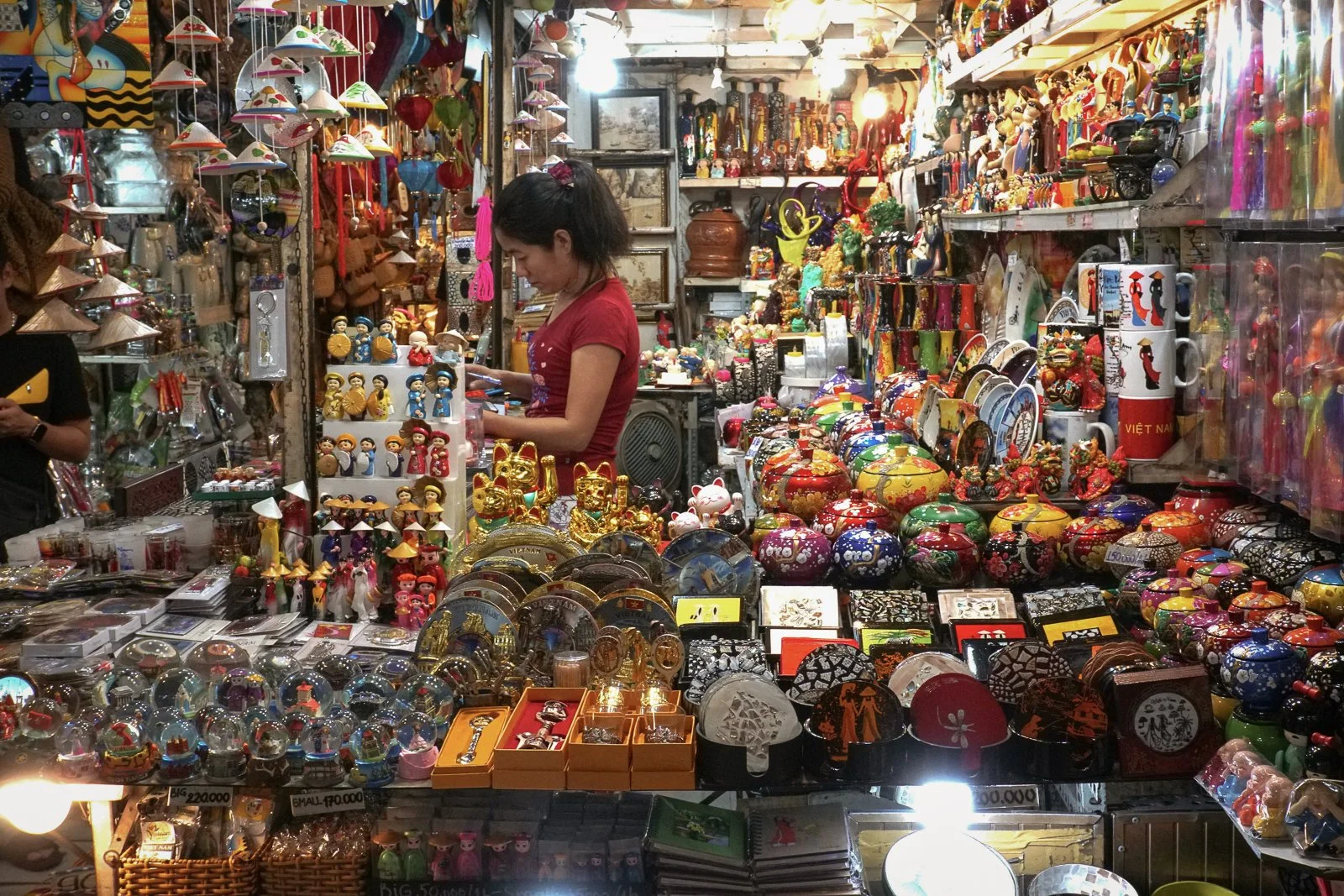 A packed souvenir stall sells lacquerware and Vietnam gifts at a Ho Chi Minh City market.