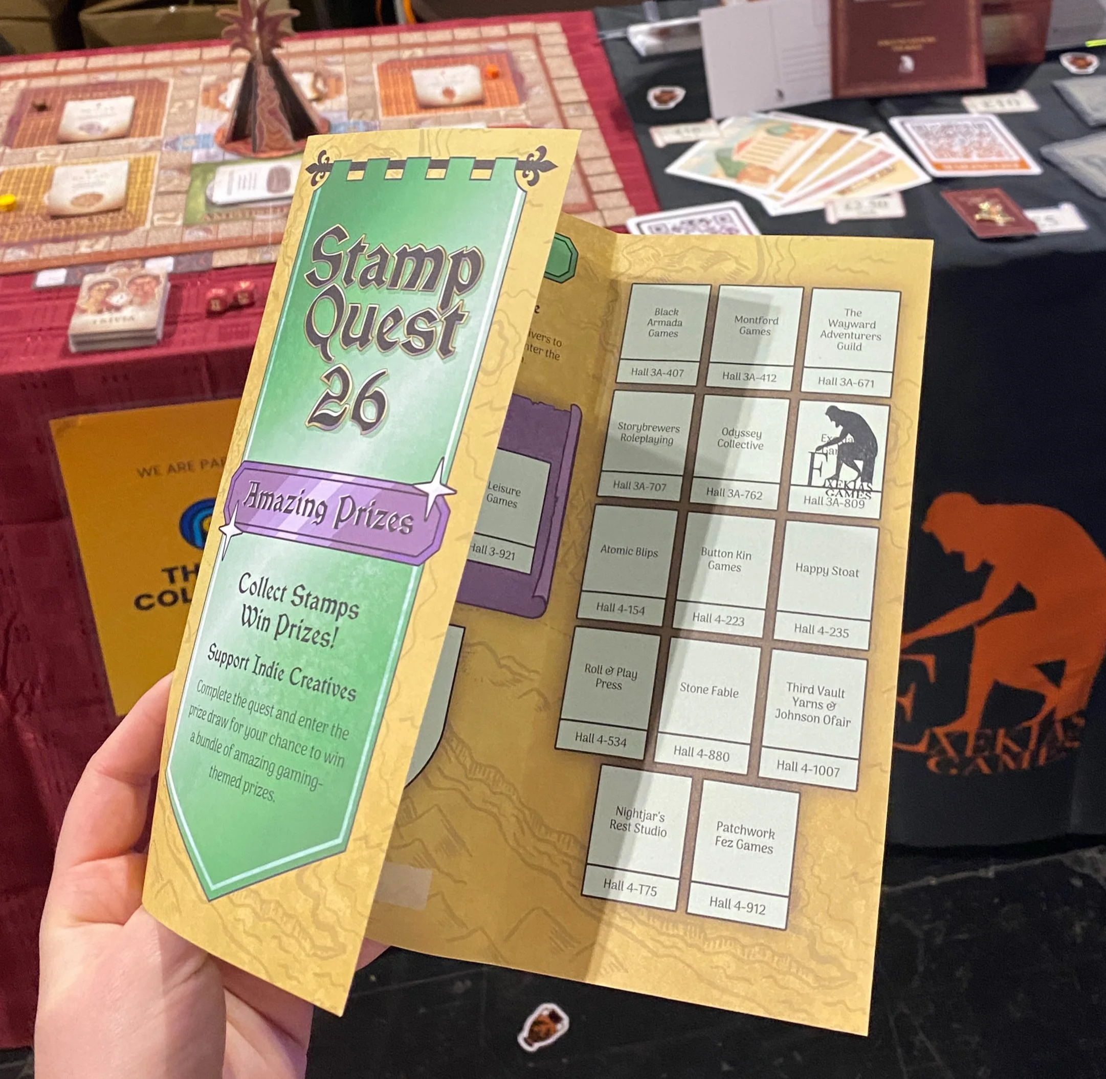 A folded leaflet for Stamp Quest 2026 with boxes for stamps from several independent publishers. The Exekias Games box has been stamped with the company's logo