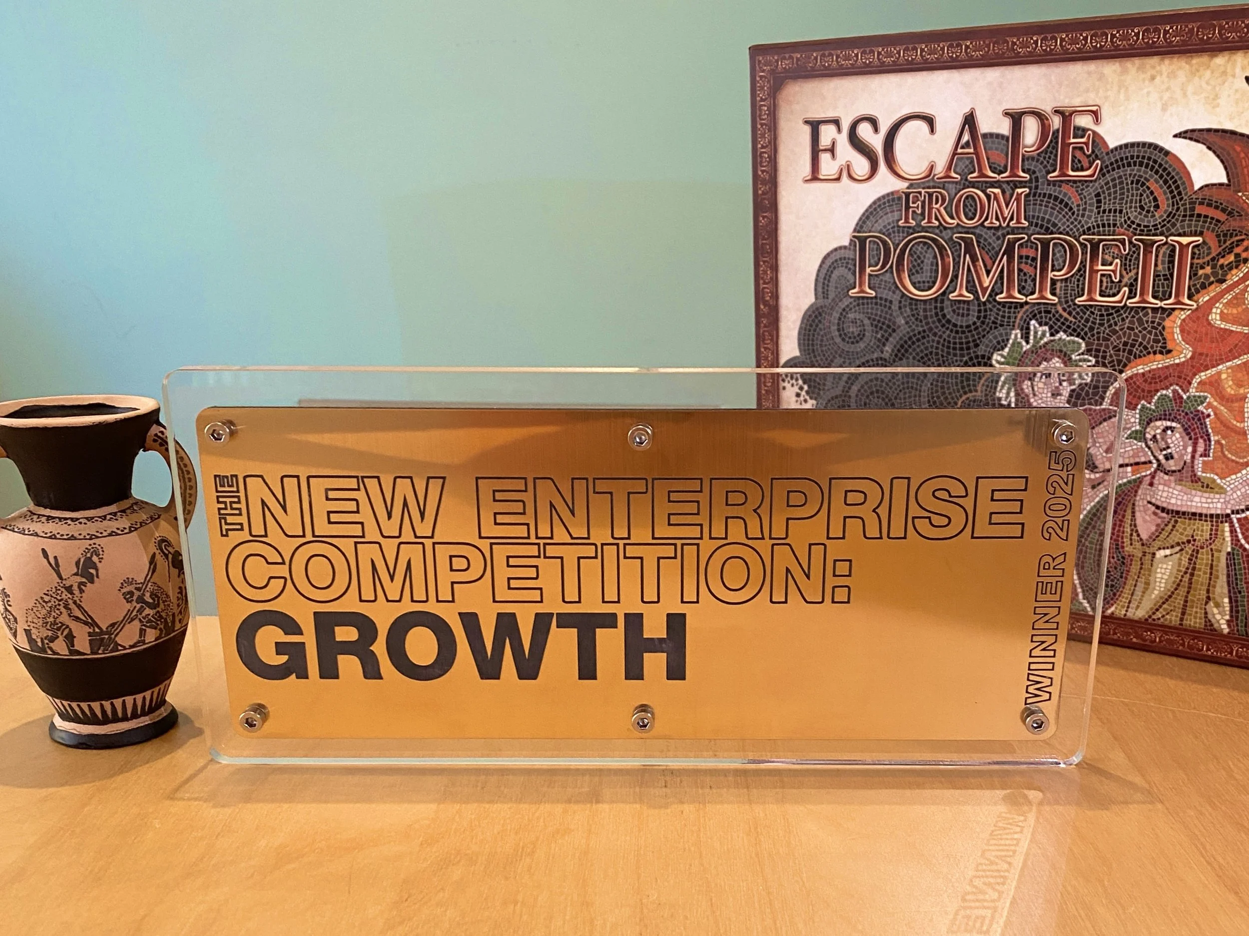 Award plaque with Escape From Pompeii board game in the background
