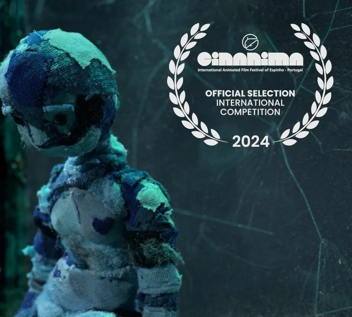 Teddy bear made of colorful, patchwork fabric with a worn, distressed appearance, in front of a dark background with the festival logo and text for the Espinho International Animated Film Festival 2024.