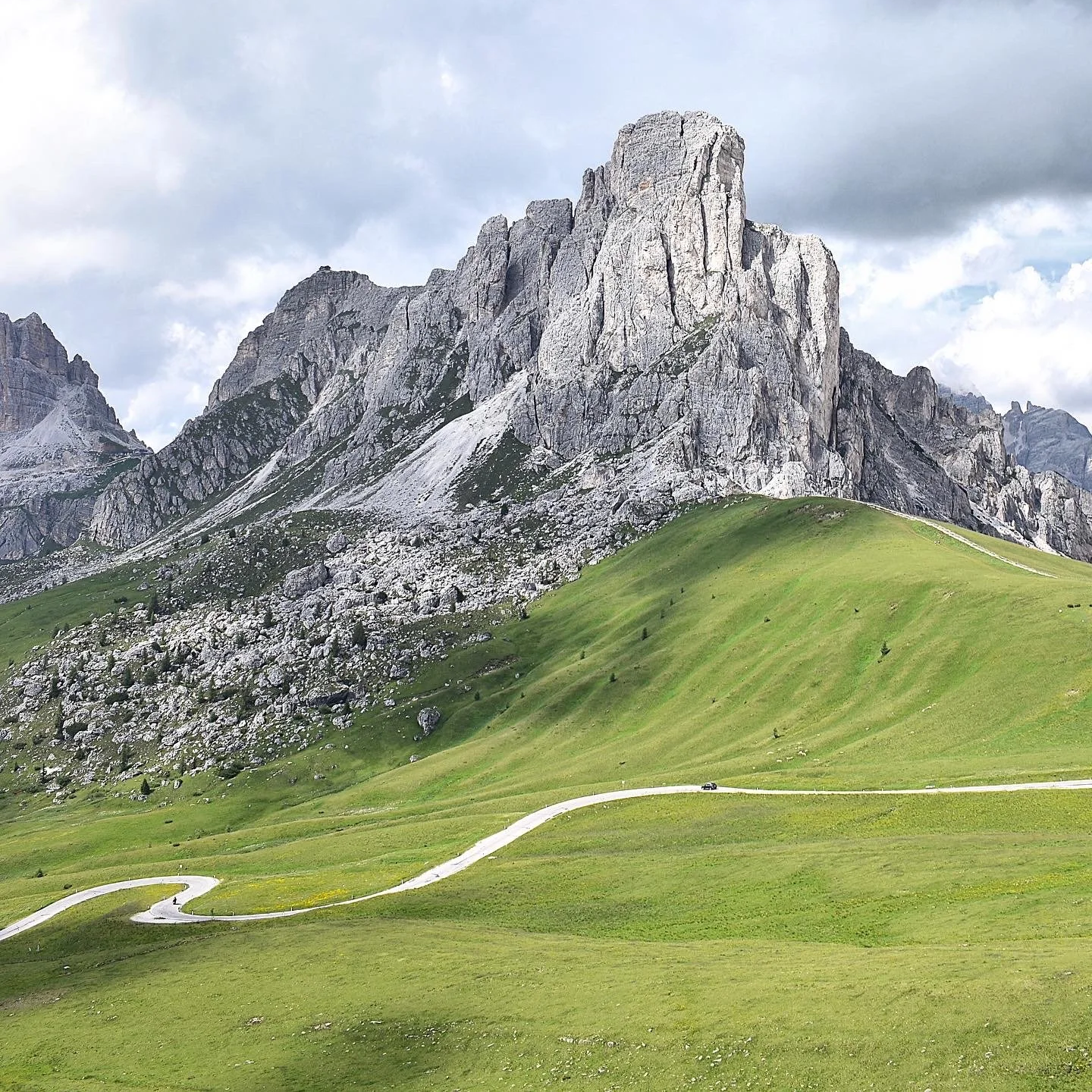 Une montagne érigée avec une prairie verte en bas, et le chemin d'un col