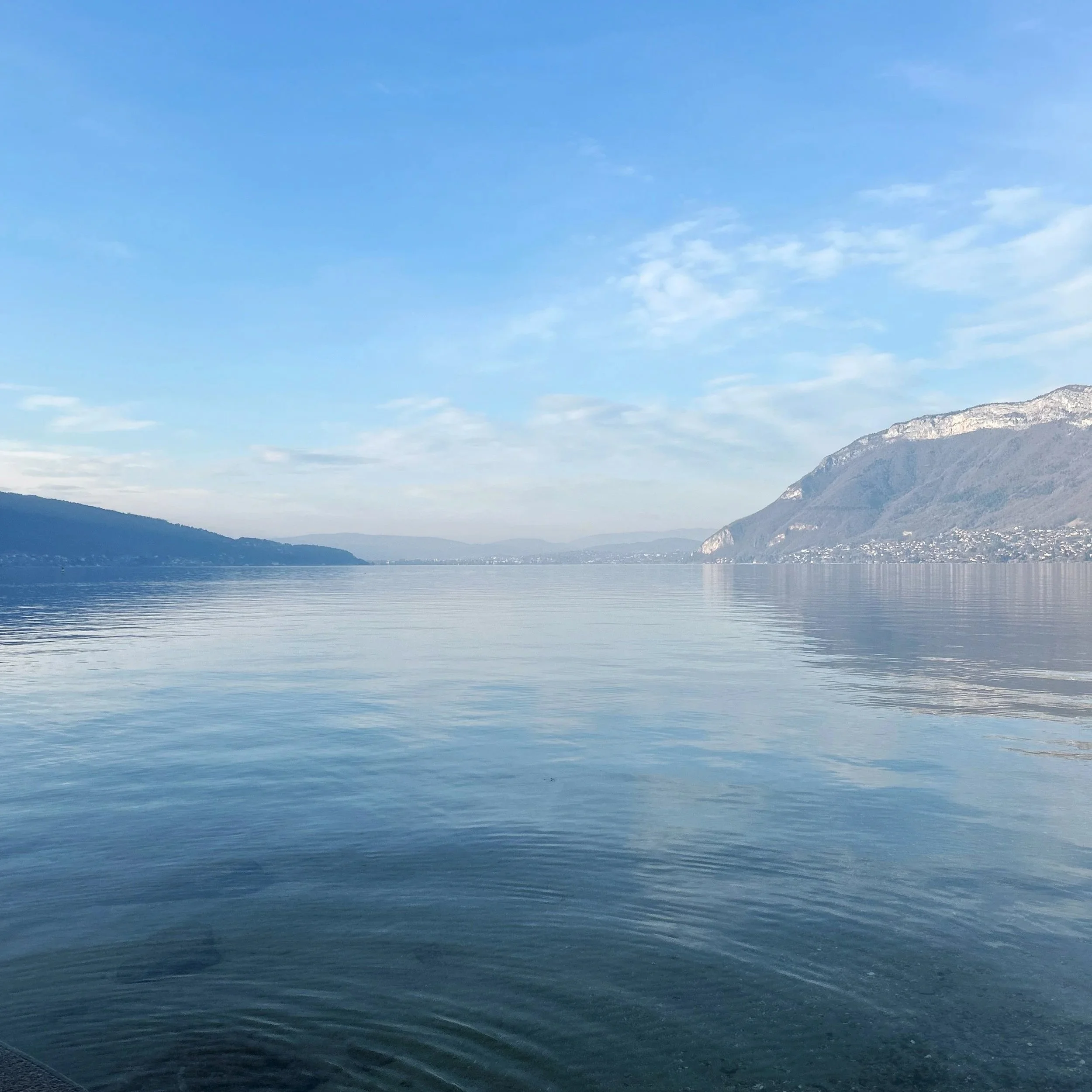 Photo d'un lac hivernal, l'eau et calme et lisse comme apaisée, le lac est bordé de montagnes