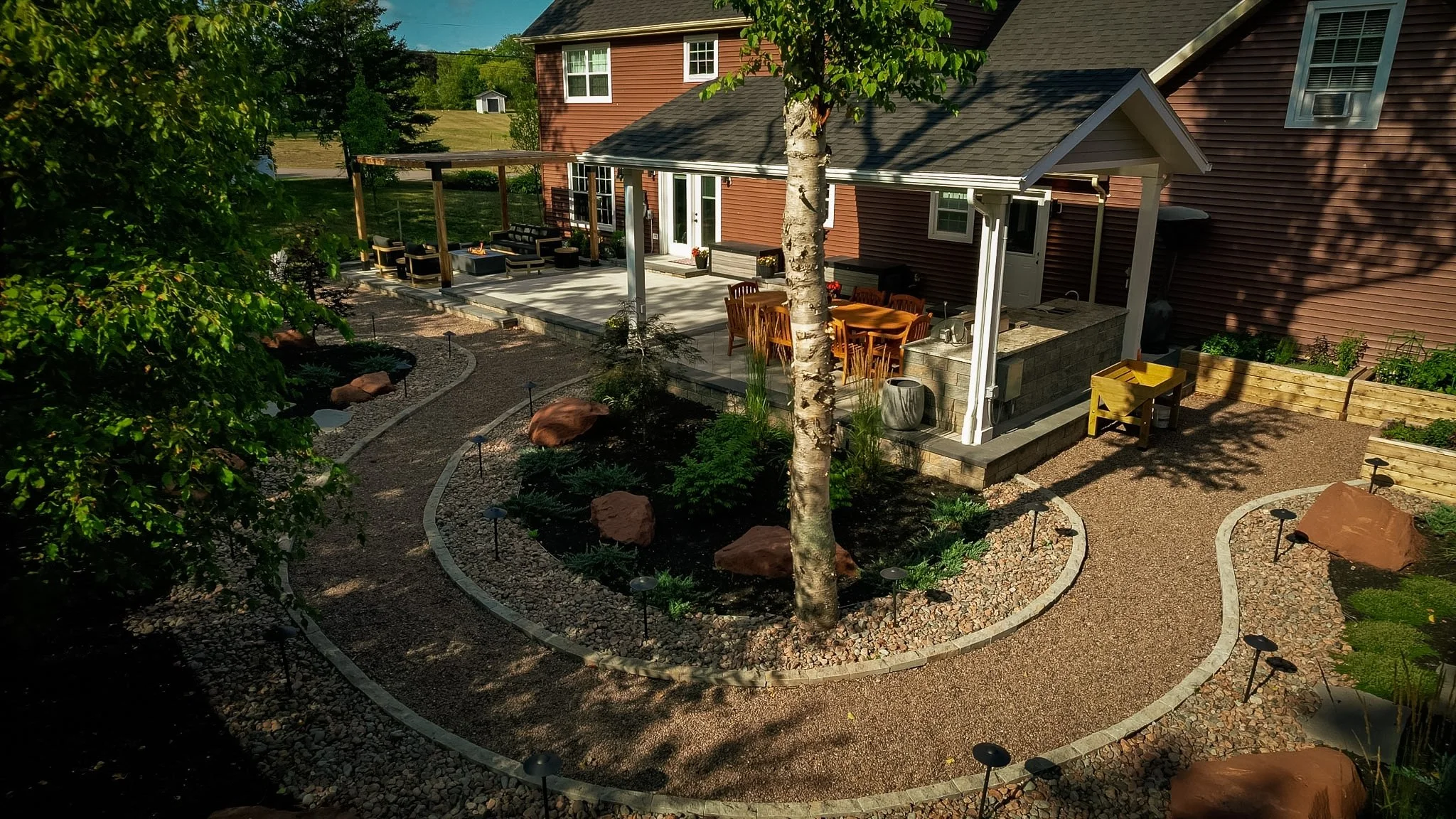 - Gravel paths with outdoor lighting
- Gardens with river rock and boulders
- Mulched gardens
- Gazebo with outdoor kitchen dining area