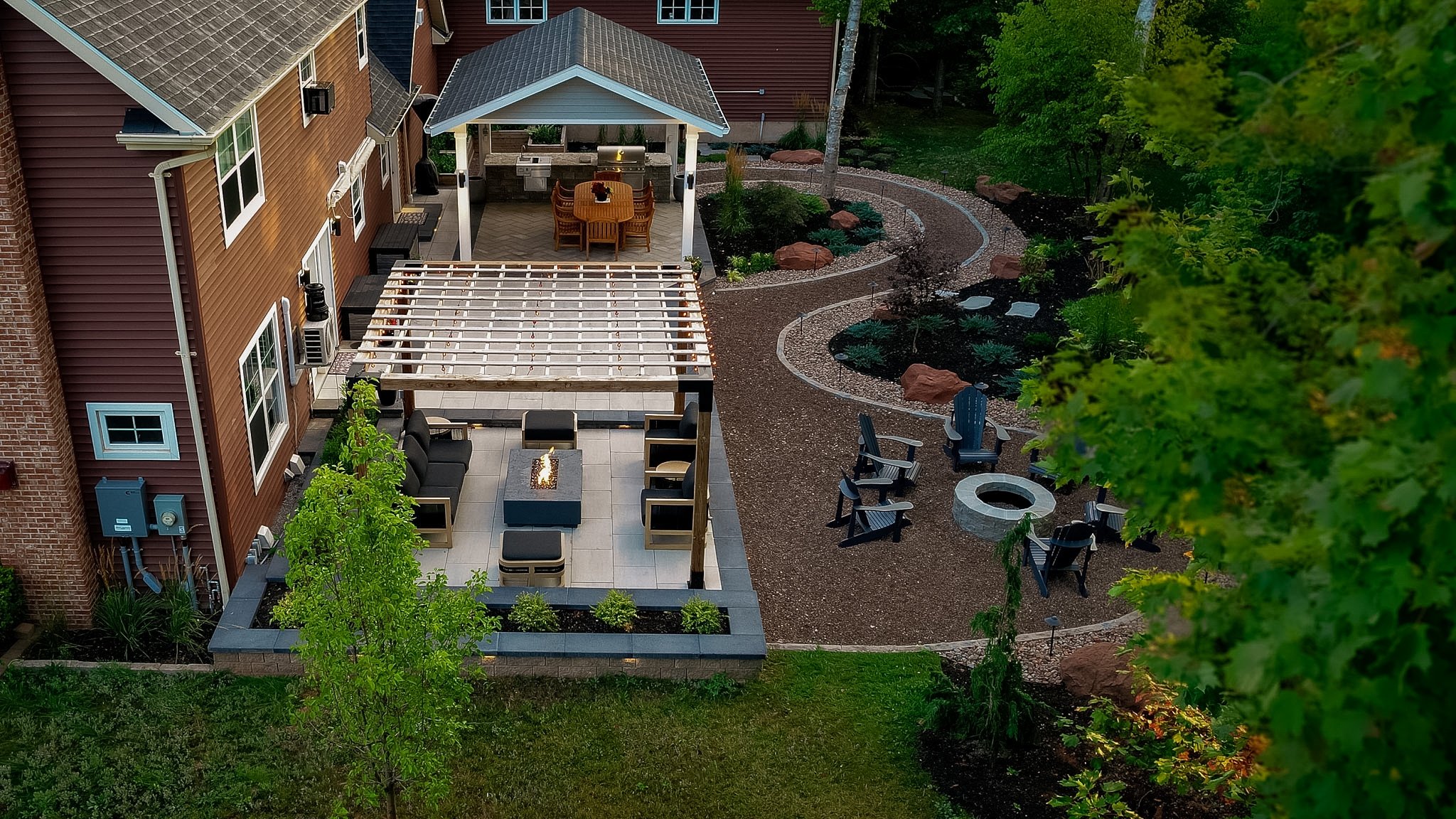Landscape design a pergola with outdoor fire table and lounge area, gazebo with dining and outdoor kitchen, and meandering paths. 