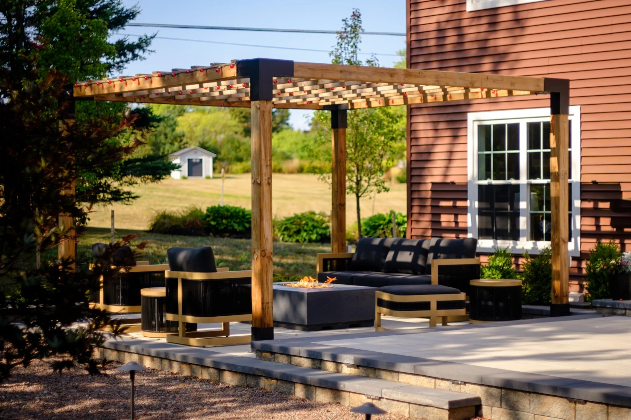 Wooden pergola with metal brackets. Outdoor fire table, lounge area with elevated patio spaces 