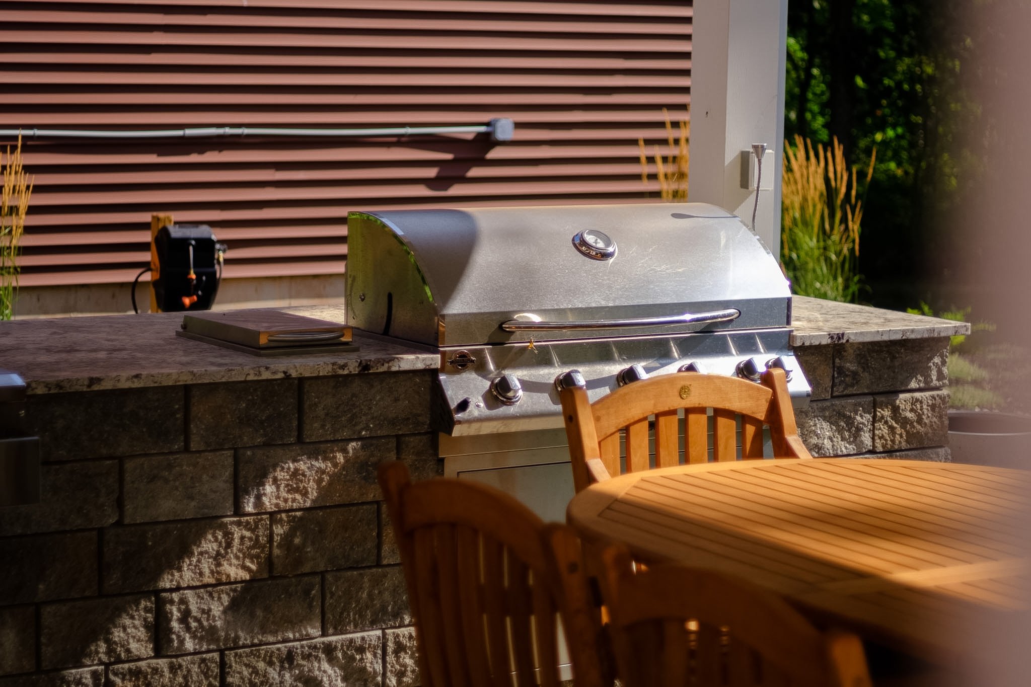 Stainless steel large barbecue insert in a stone outdoor kitchen with marble countertops 