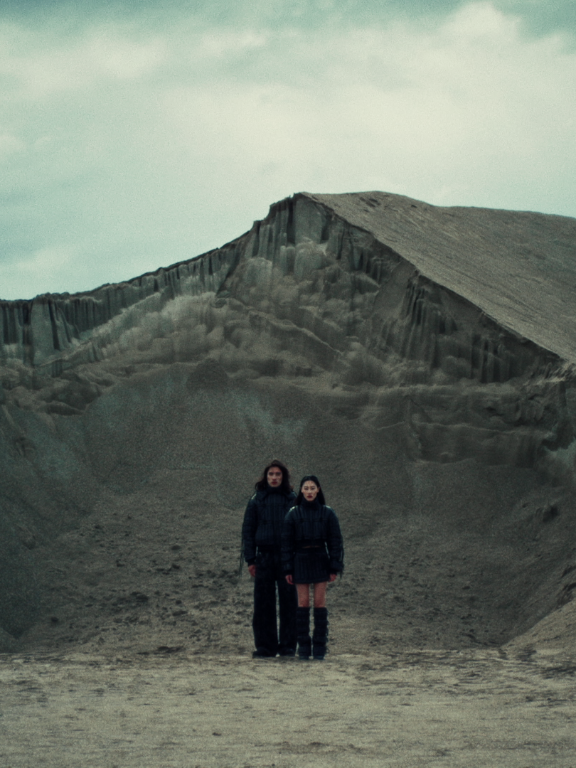 Zwei Frauen stehen in einer kargen, vulkanähnlichen Landschaft mit großen Erhebungen im Hintergrund. Editorial Hochzeitsfotos