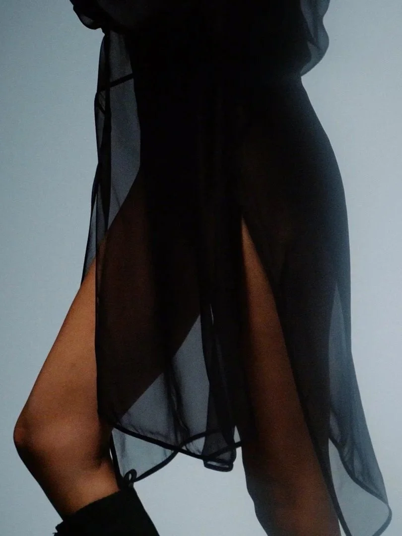 Nahaufnahme einer Person in einem schwarzen transparenten Kleid, das die Beinen und den Körper teilweise sichtbar macht. Editorial Hochzeitsfotos