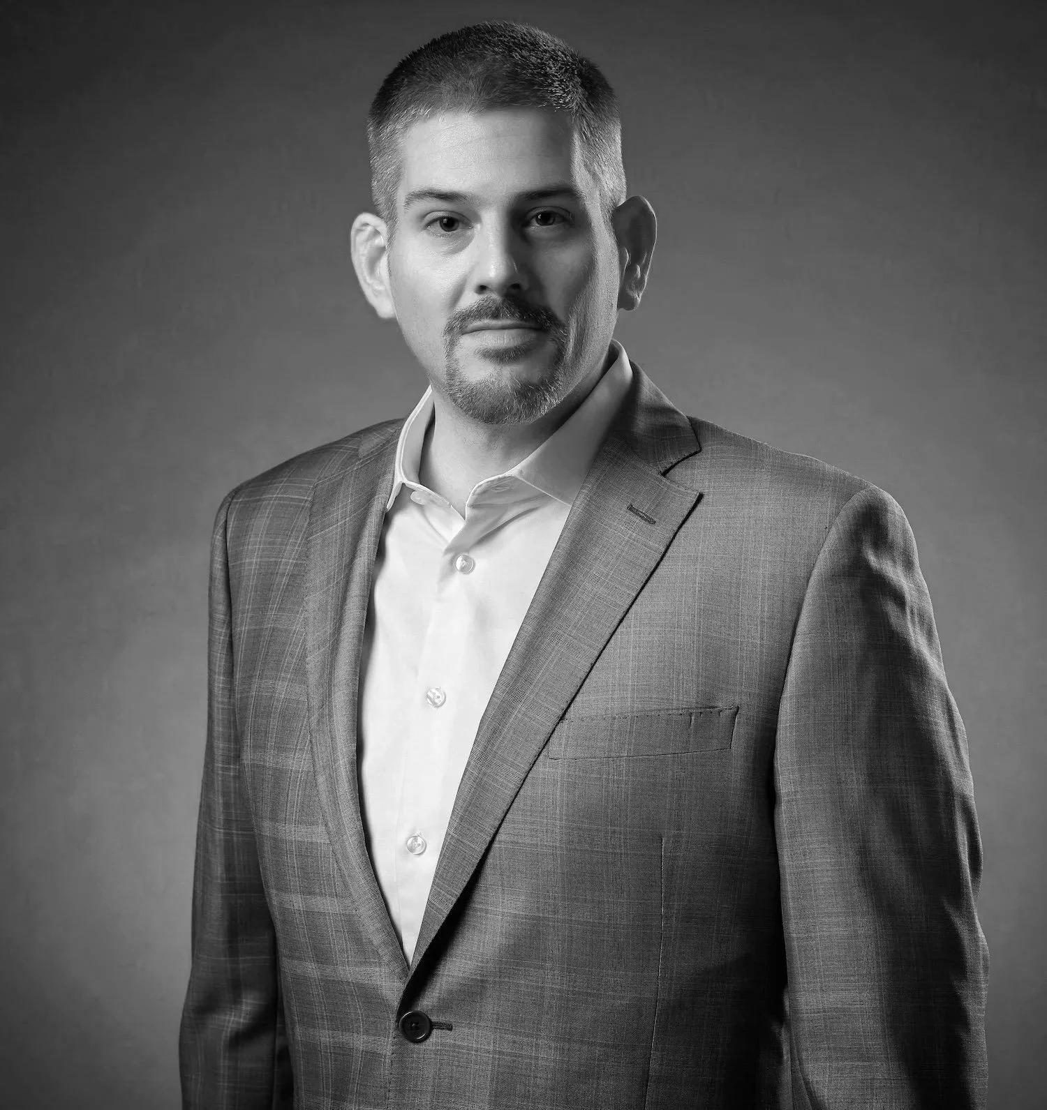 Black and white portrait of a man in a suit, looking at the camera.