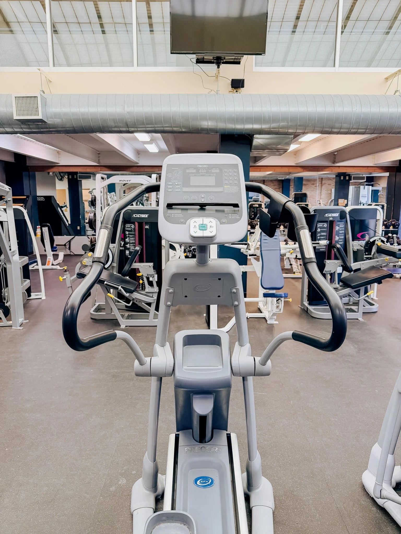 Empty elliptical exercise machine with digital display in a gym.