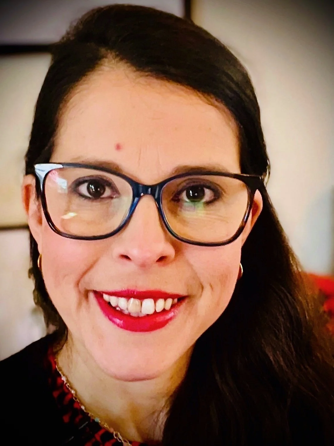 A woman with dark hair and glasses smiling at the camera.