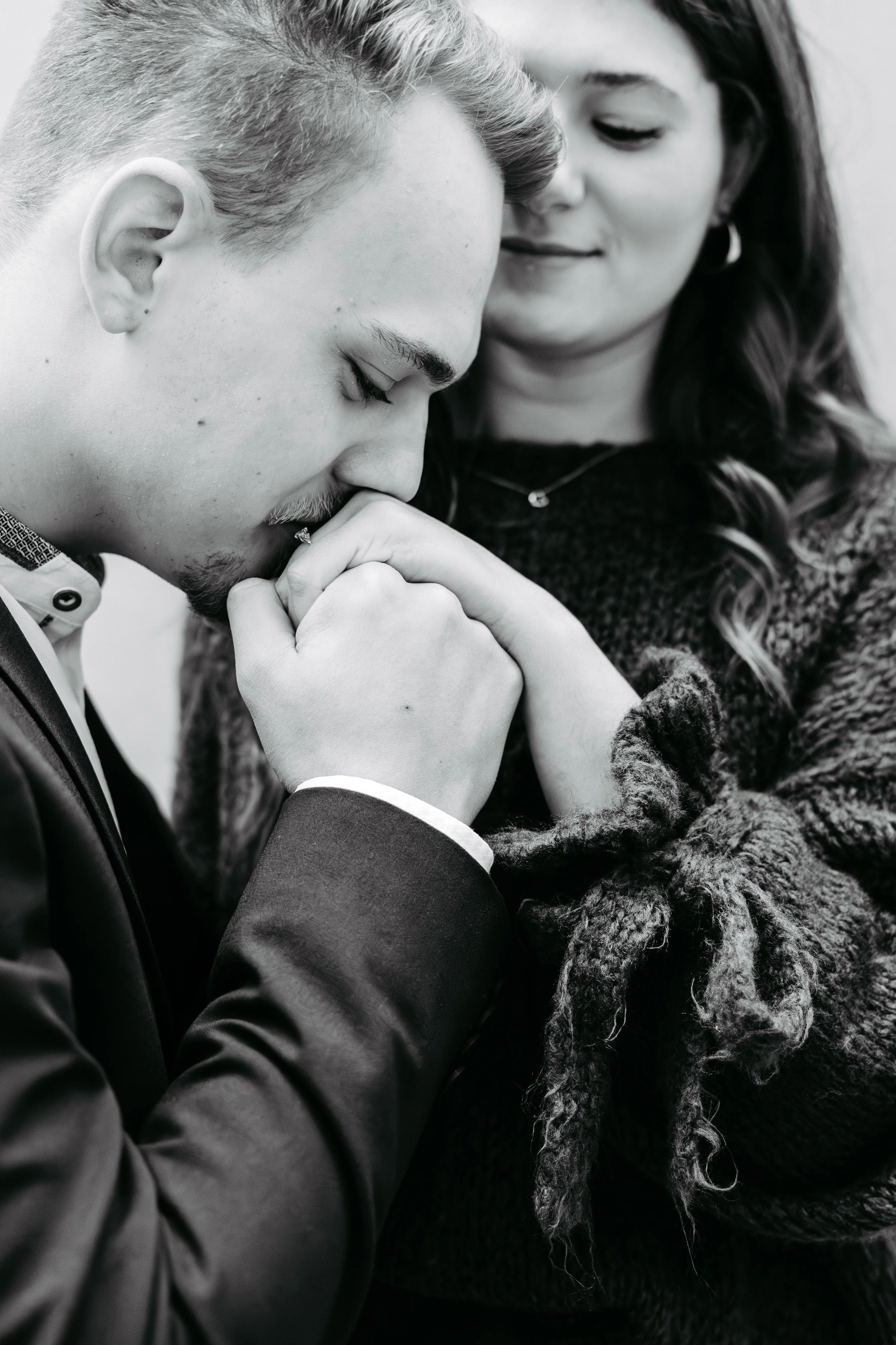 Ein Mann und eine Frau, die sich die Hand halten und in einer emotionalen Geste ihre Hände aneinanderlegen, mit geschlossenen Augen und einem sanften Ausdruck auf ihren Gesichtern.