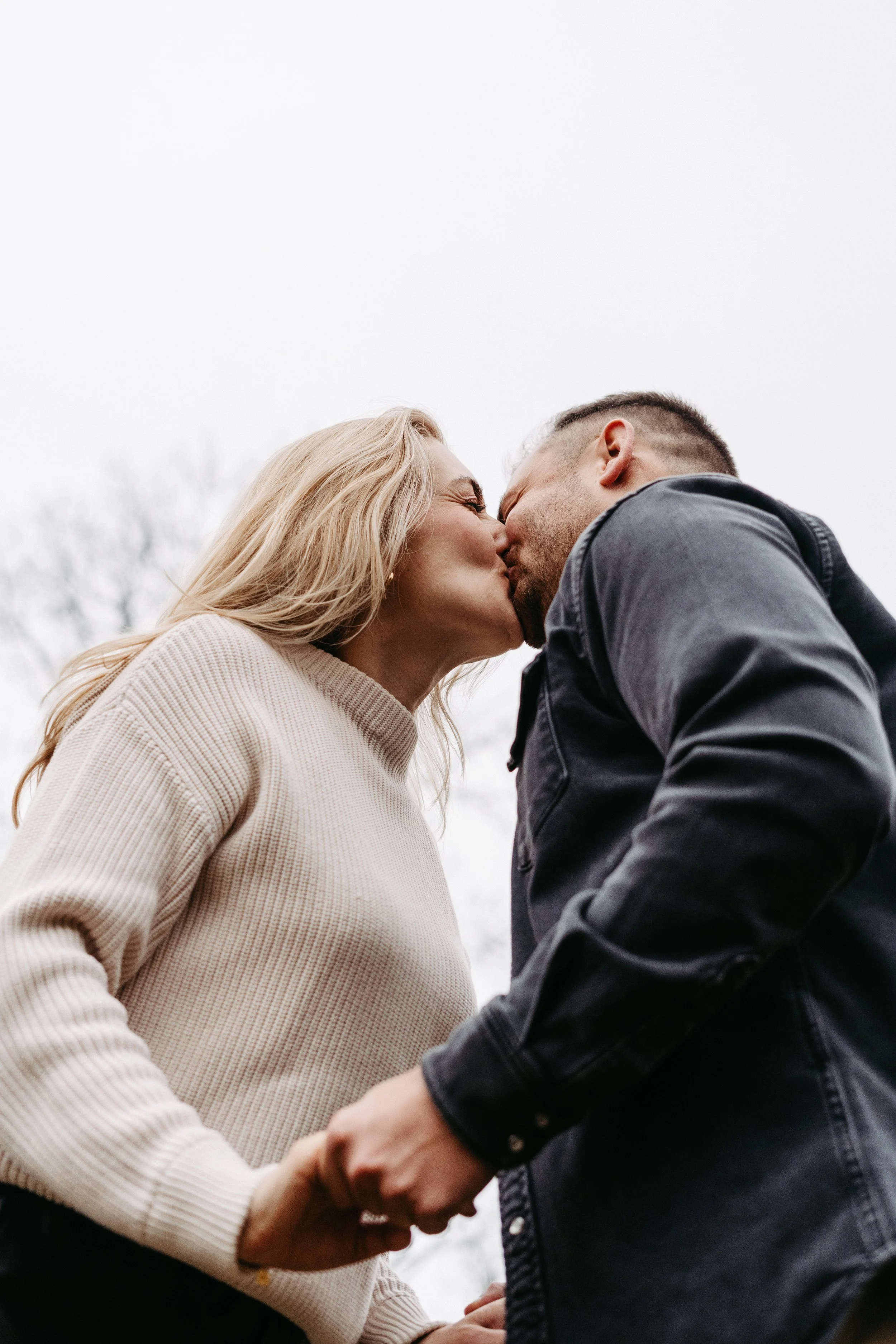 Ein Paar küsst sich im Freien bei bewölktem Himmel.