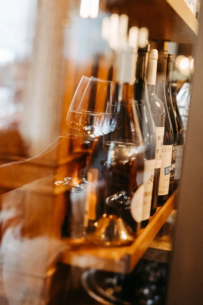 Verblasster Weinglas und Weinflaschen auf einem Regal in einer gemütlichen Umgebung.