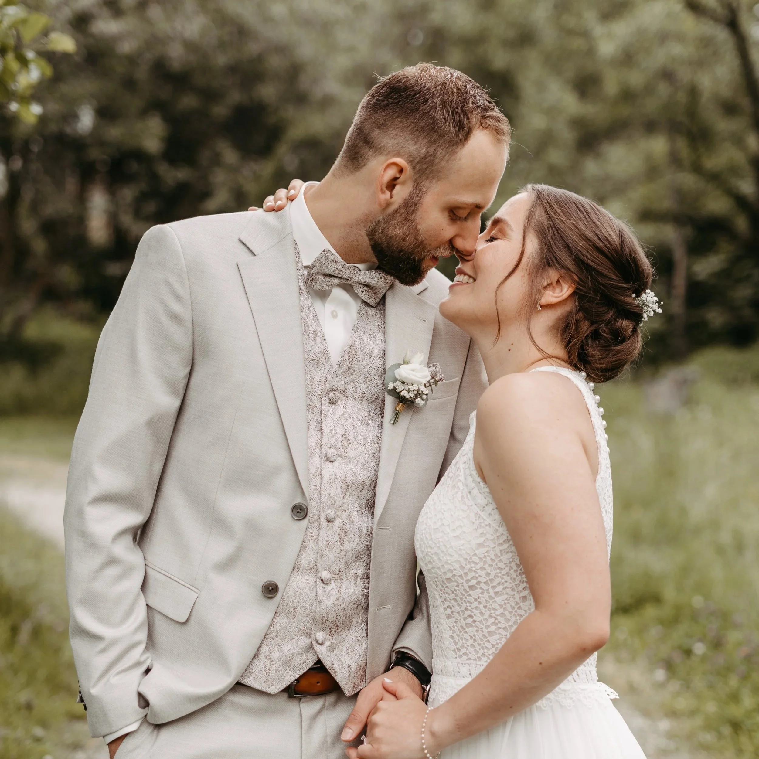 Ein Brautpaar auf einer Wiese bei ihrer Hochzeit, küsst sich sich.