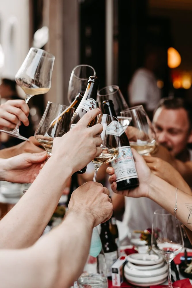 Menschen stoßen mit Wein- und Biergläsern auf einer Feier an.