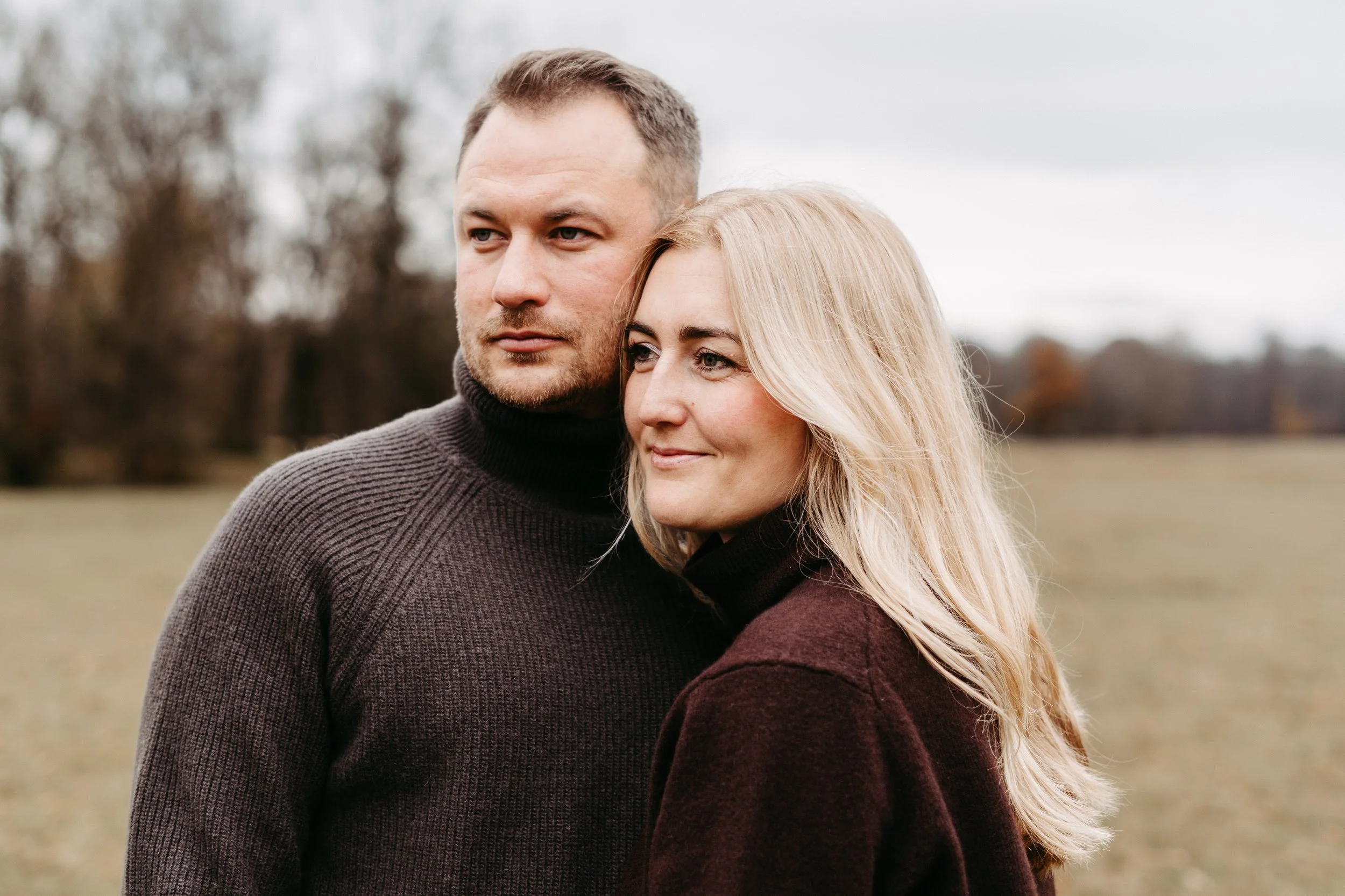 Ein Mann und eine Frau stehen im Freien auf einem Feld, schauen in die Ferne.
