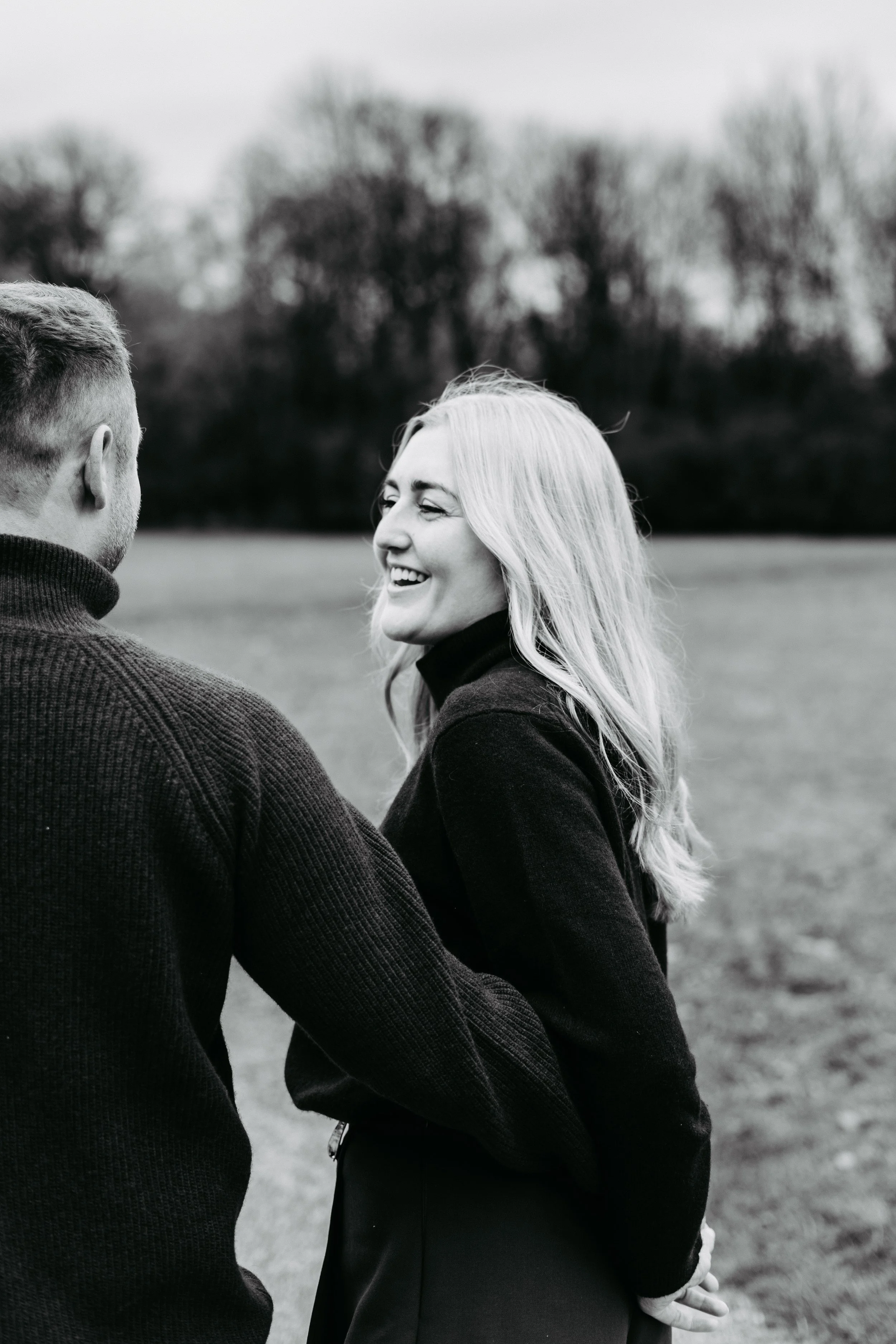 Zwei Menschen, ein Mann und eine Frau, lachen und reden im Freien auf einer Wiese, schwarz-weiß fotografie.