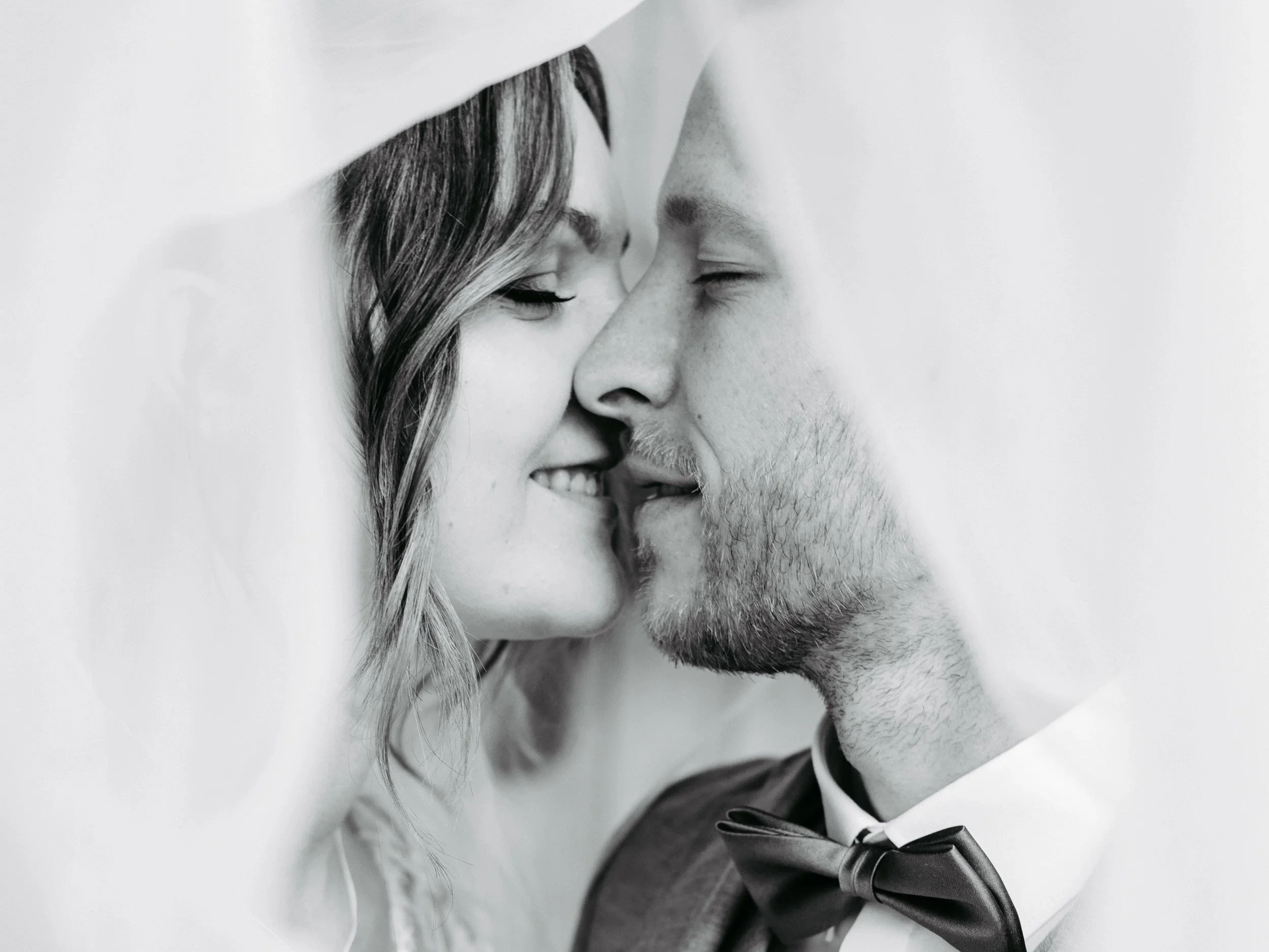 Ein glückliches Brautpaar bei einer Hochzeitszeremonie, das sich mit der Stirn aneinander legt.