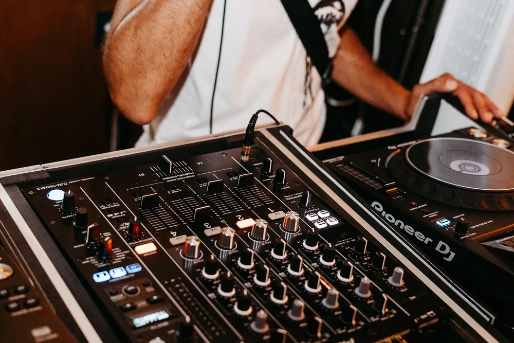 DJ mit Mixer und Plattenspieler beim Auflegen in einer Bar oder einem Club.