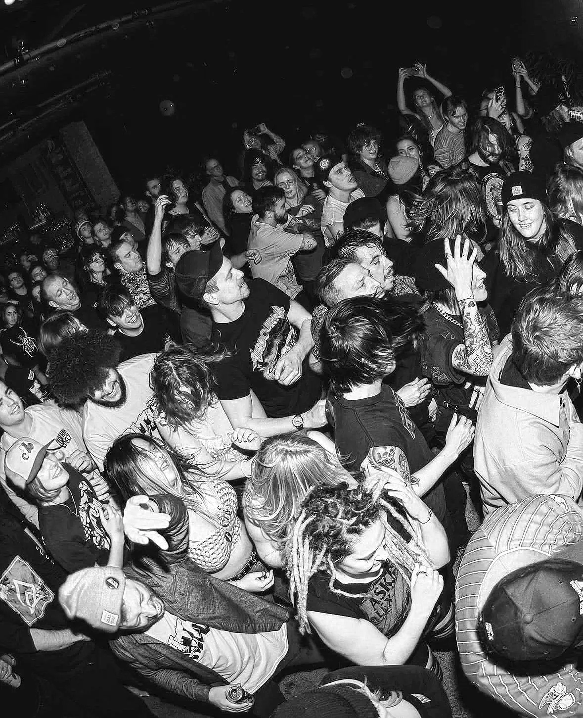 A black and white photo of a crowded concert or party with people dancing and enjoying the music.