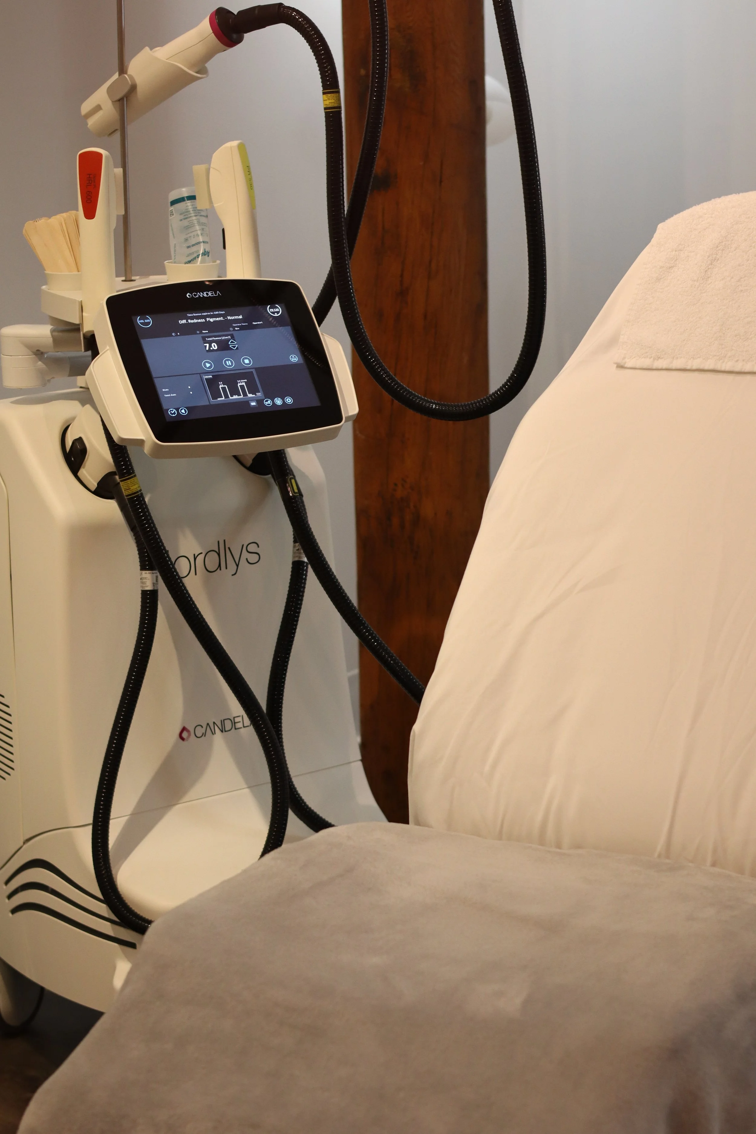 Medical treatment device next to a beige reclined chair with white and tan pillows, in a clinical setting.