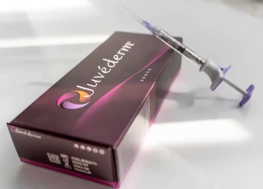 A box labeled 'Juvederm' with a medical syringe resting on top of it.