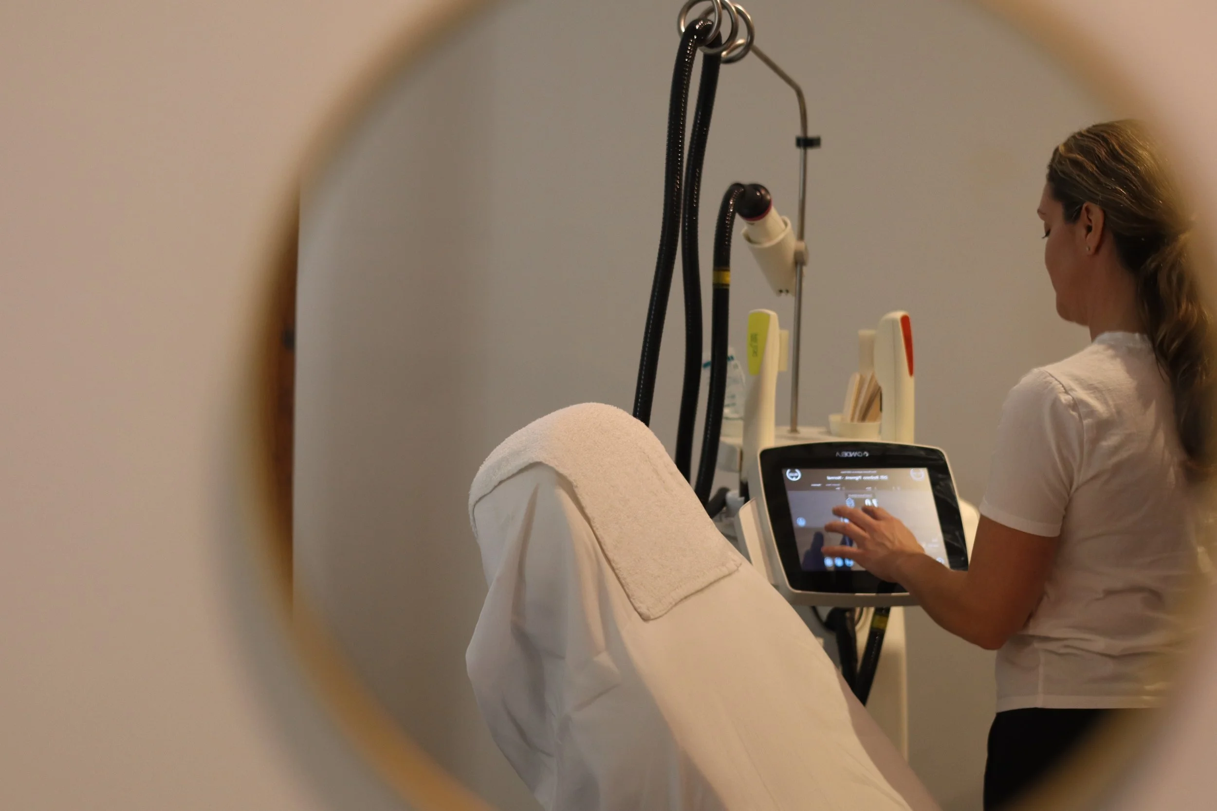 Medical professional operating a diagnostic machine in a clinical setting, viewed through a circular frame.