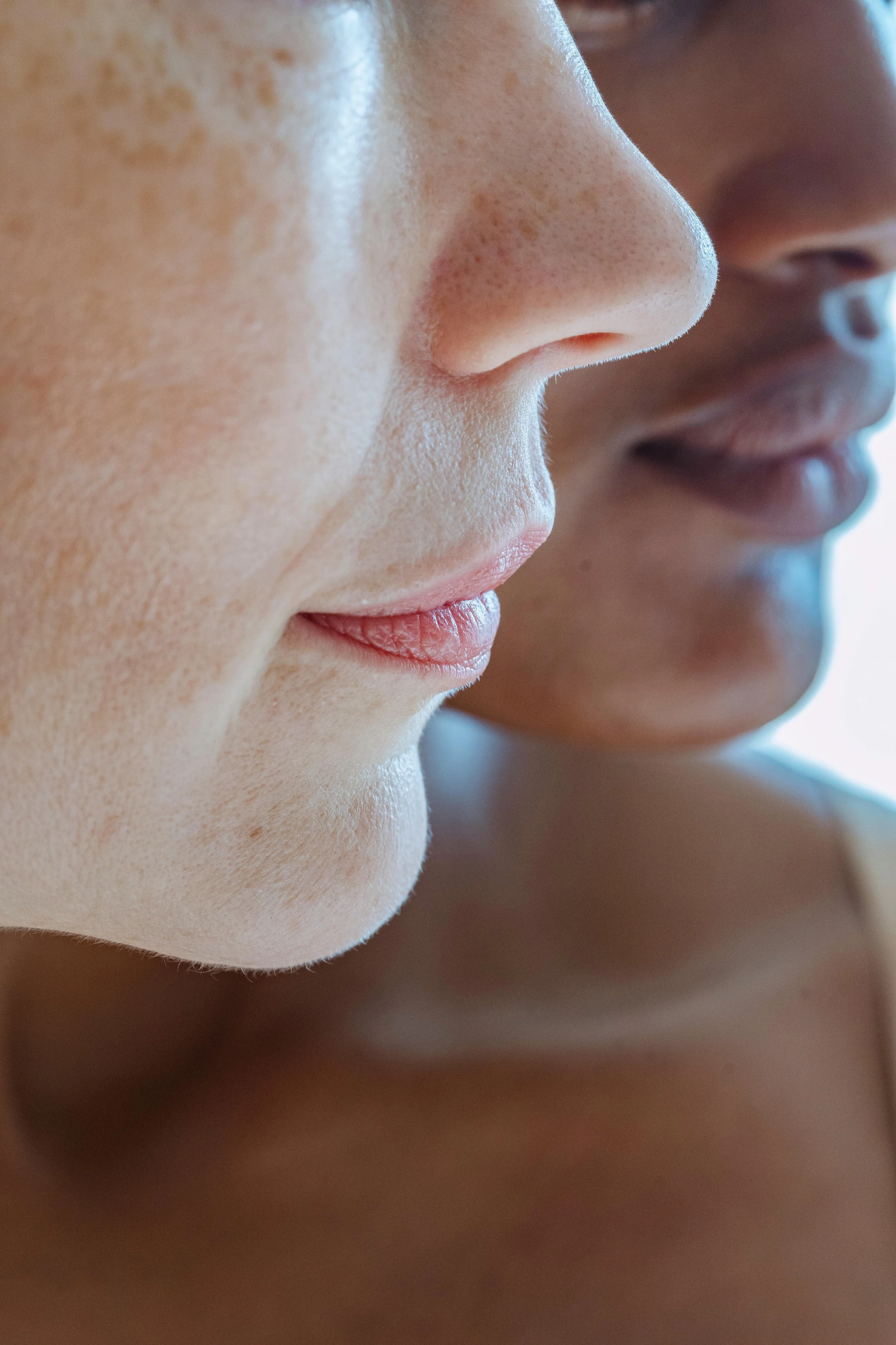 Close-up of two people with their faces close together, focusing on their noses and mouths.