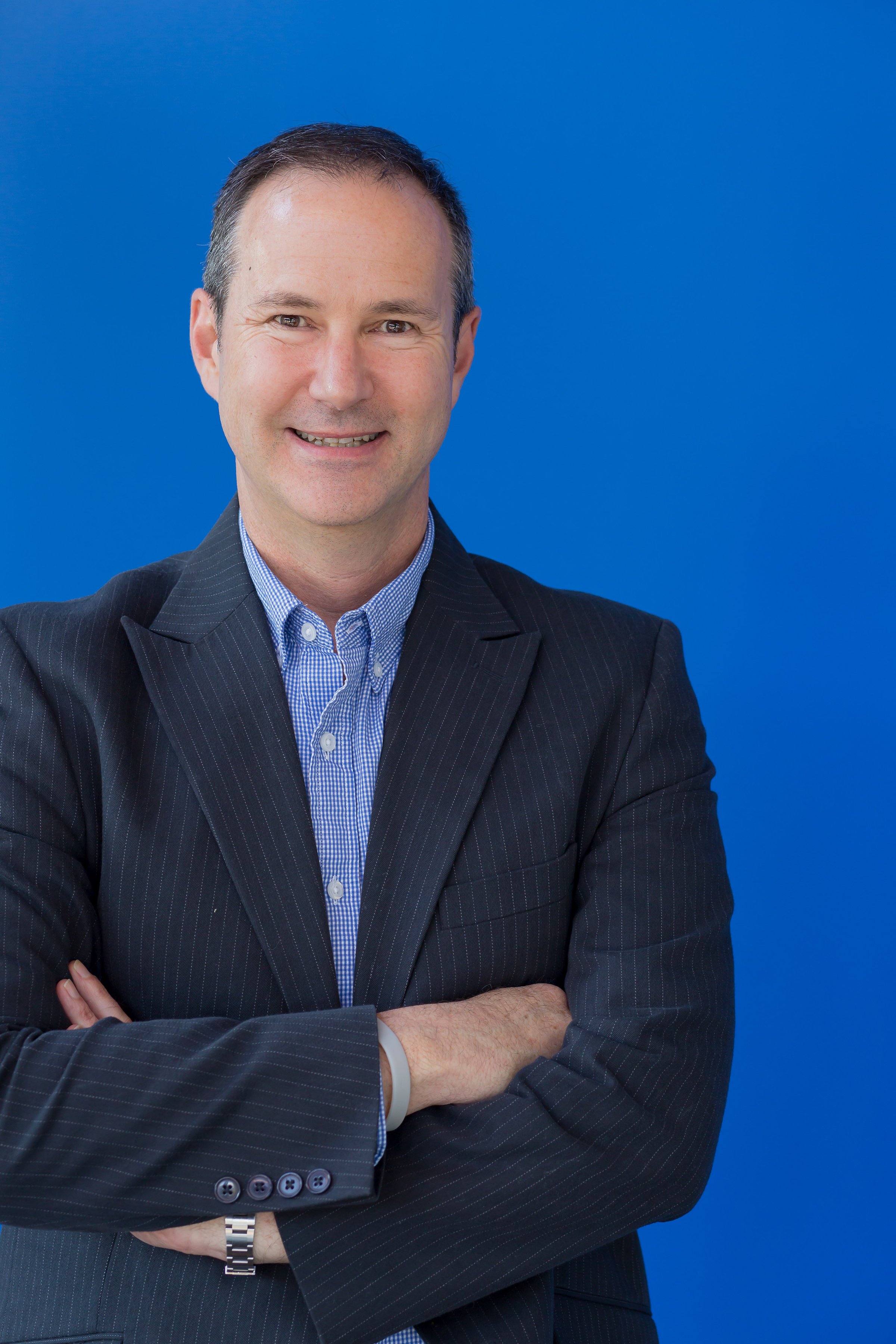 Headshot of David Barry, a smiling man, in a blue jacket and light blue shirt