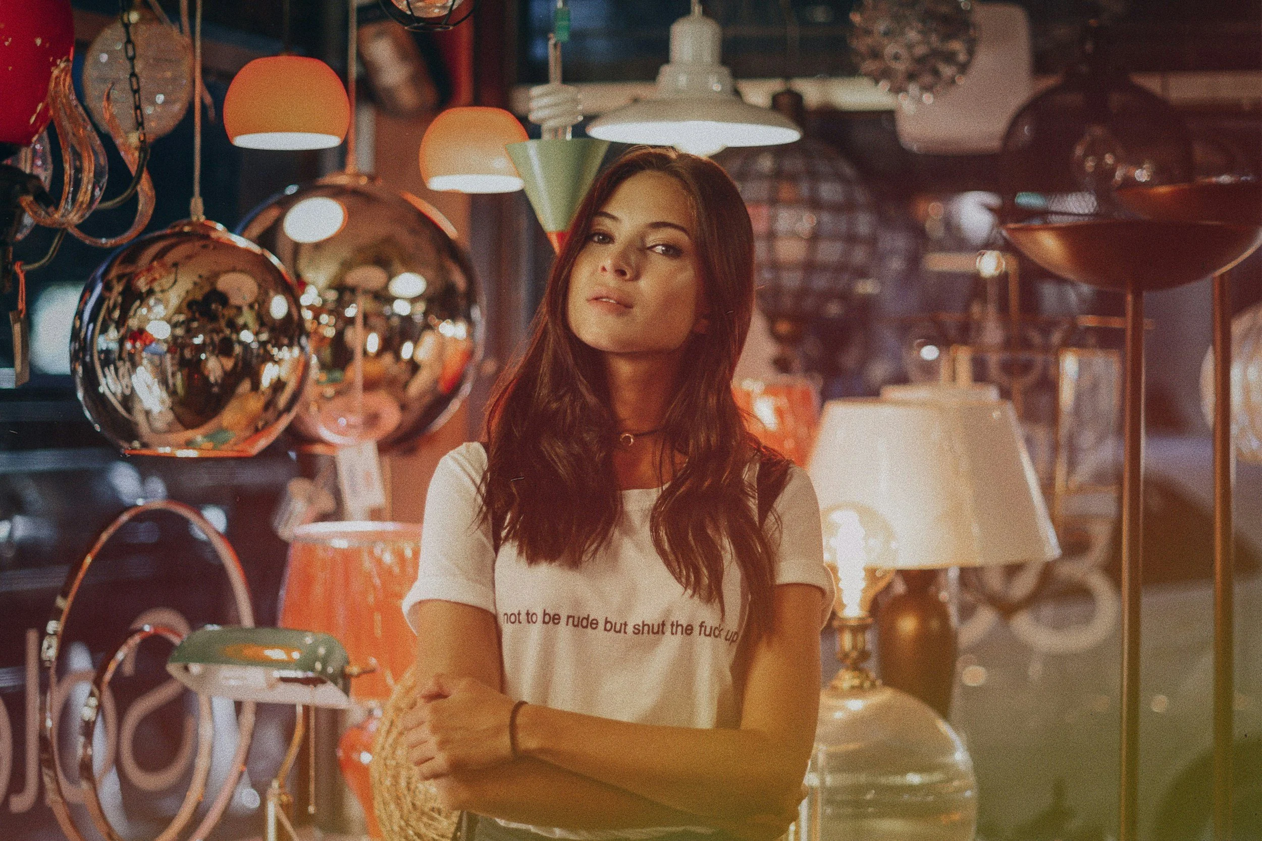 A woman with long brown hair standing among various lamps and lighting fixtures in a lighting store.