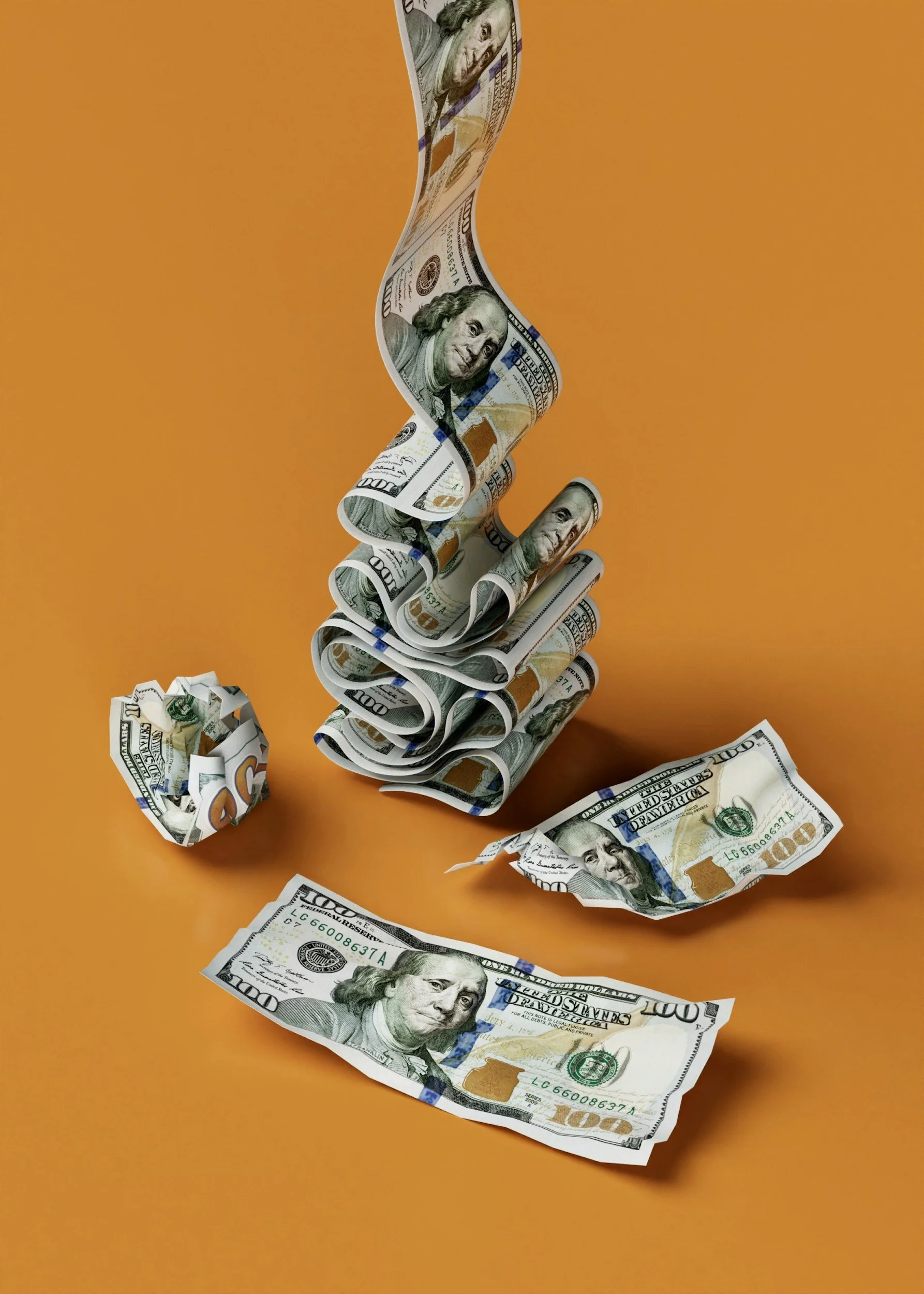 Folded and crumpled $100 bills on an orange surface with a tall, twisted stack of hundred dollar bills standing upright.